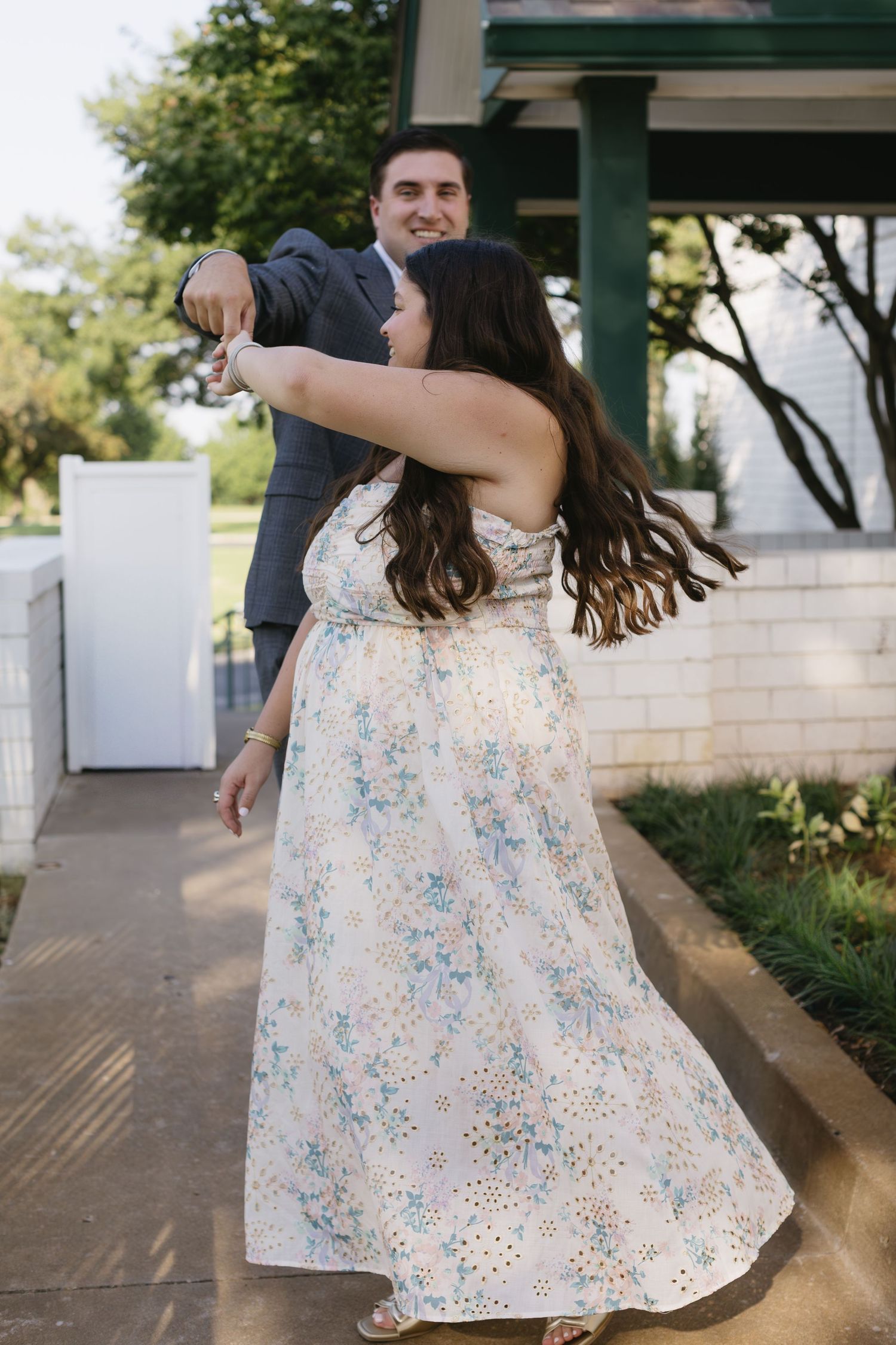 A dancing couple spins together on a patio, with her floral dress flowing in movement.