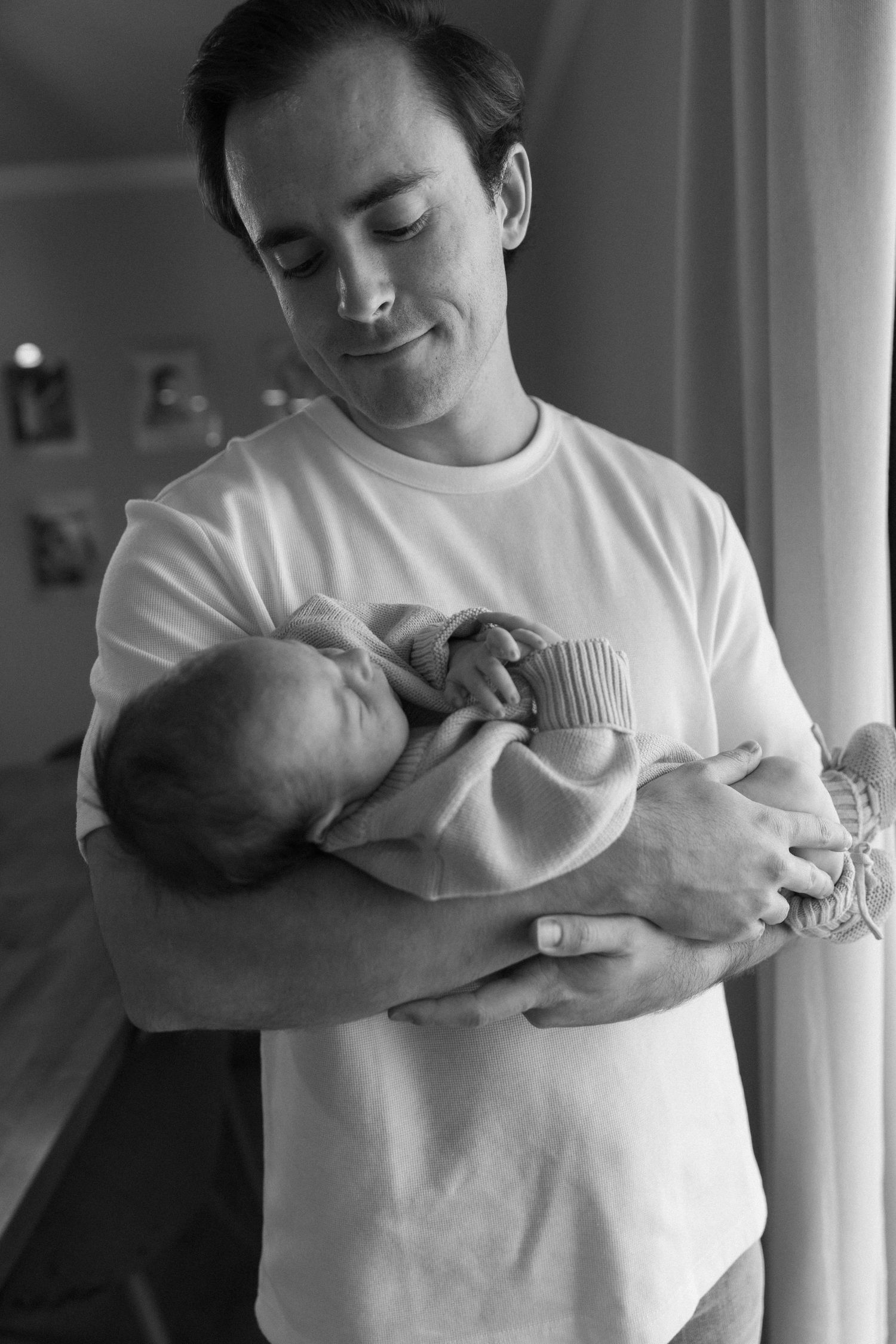 Black and white series showing gentle moments with newborn in white clothing.