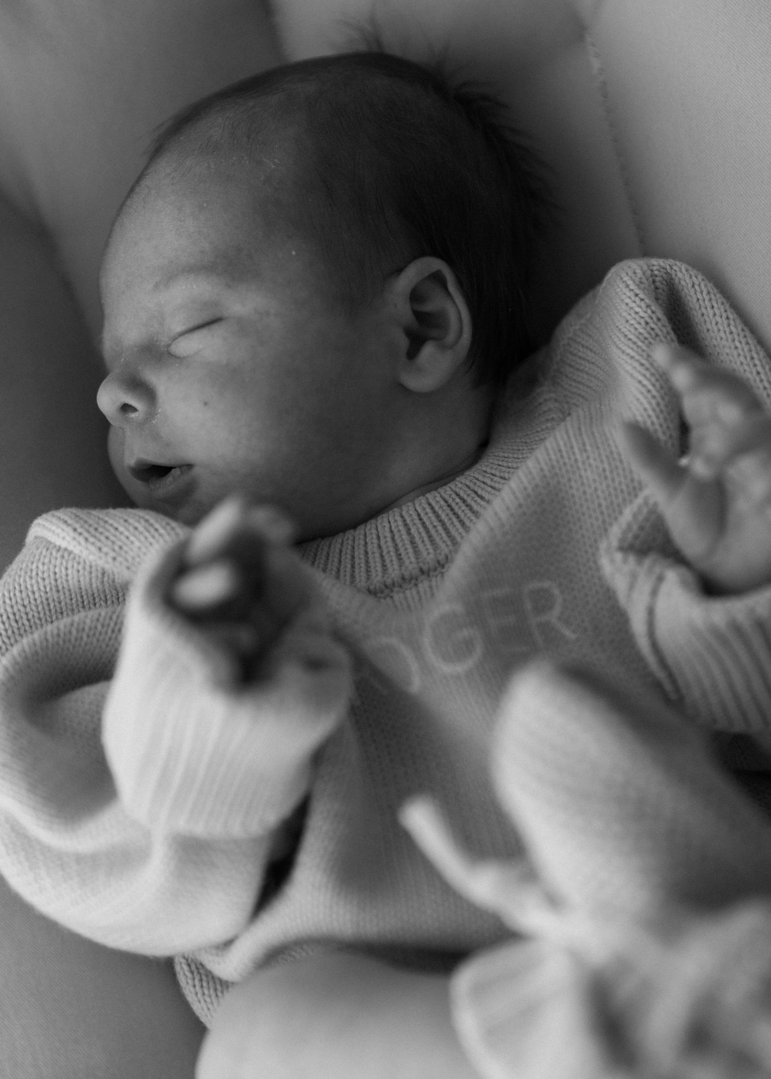 Close-up black and white images of a sleeping newborn baby in soft focus.