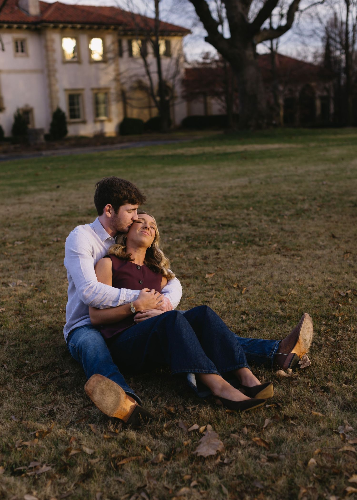 Couple lying together on grass during golden hour in romantic poses.