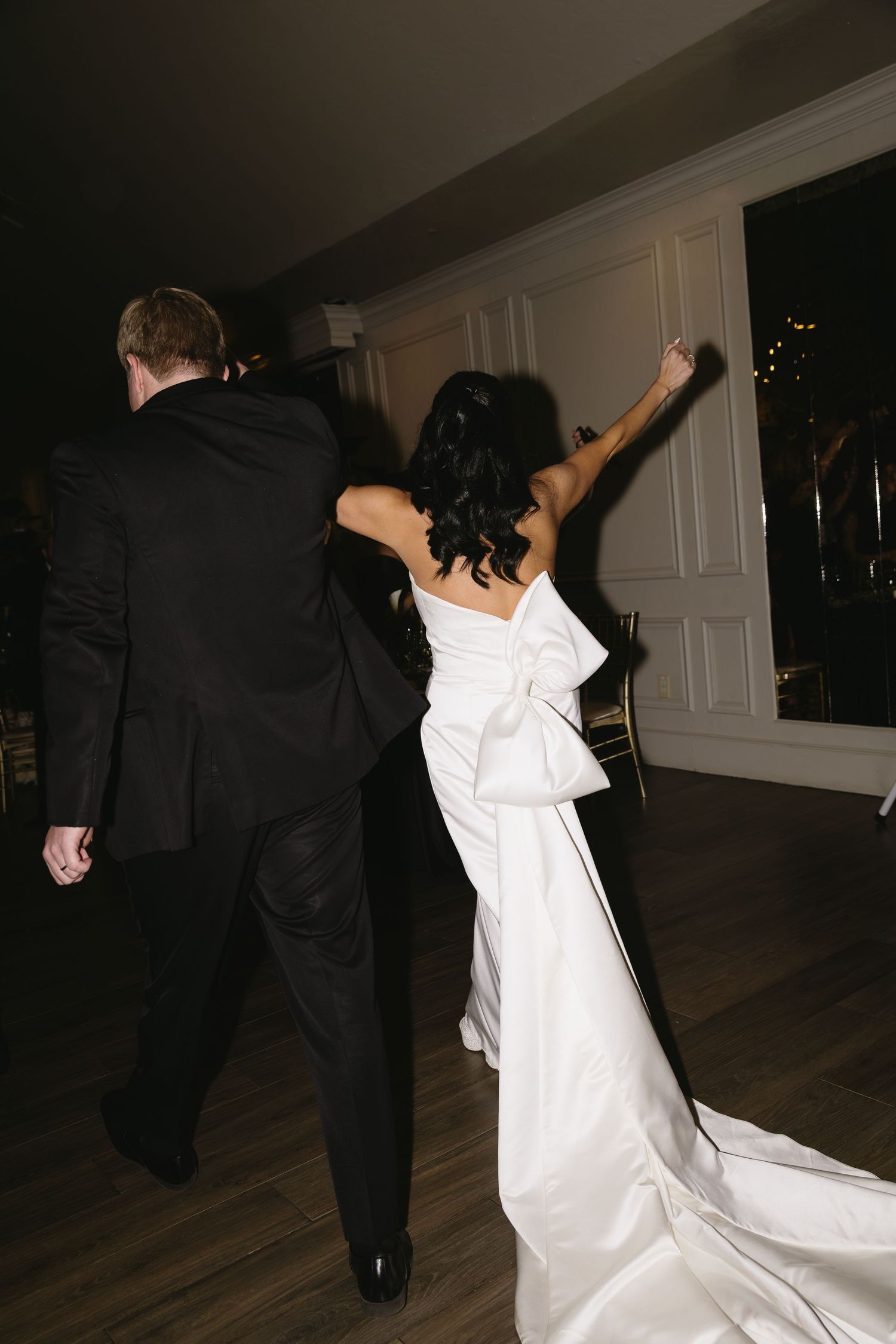 Wedding couple dancing energetically on a wooden floor during their reception.
