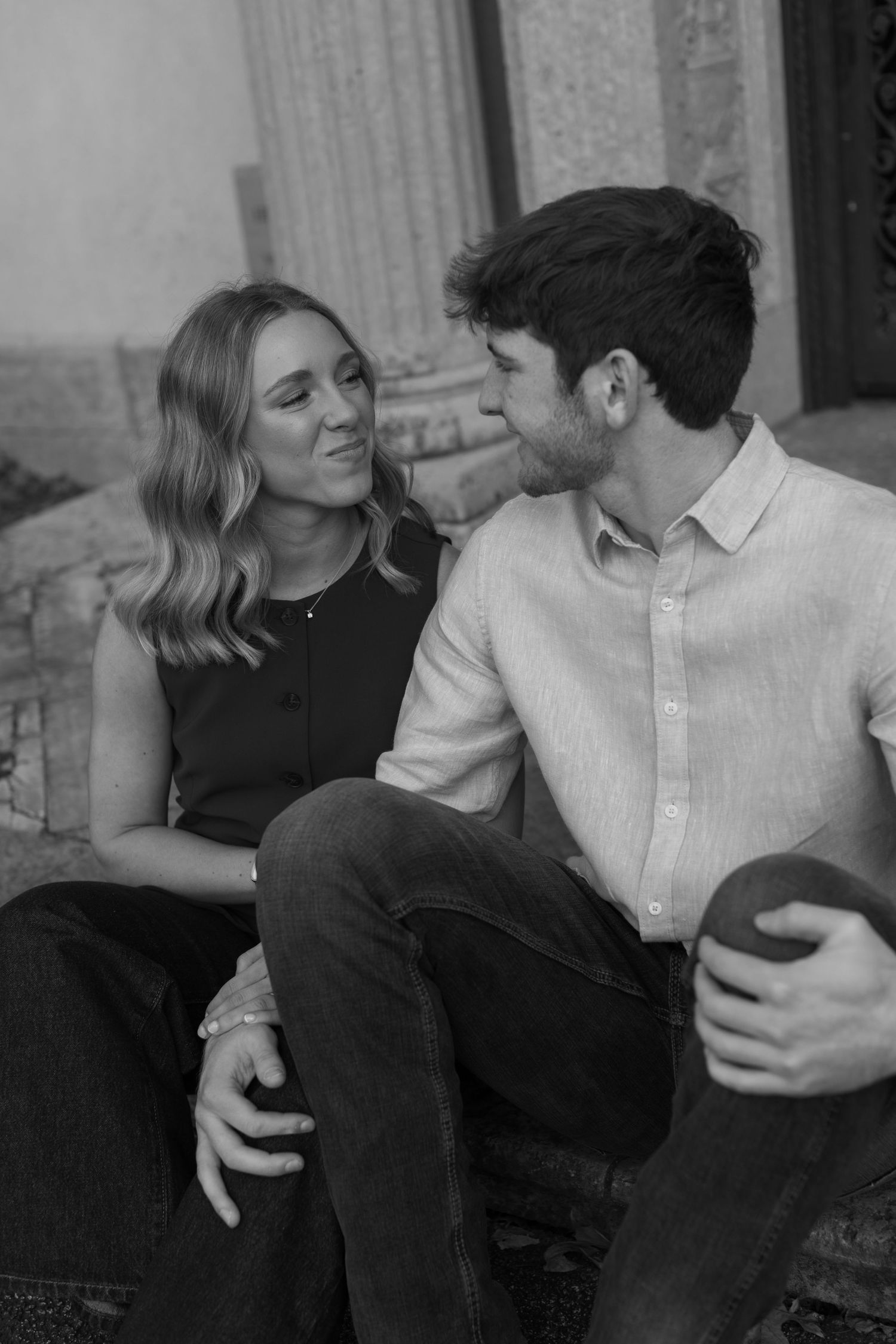 Black and white portrait of couple sitting close together and smiling.