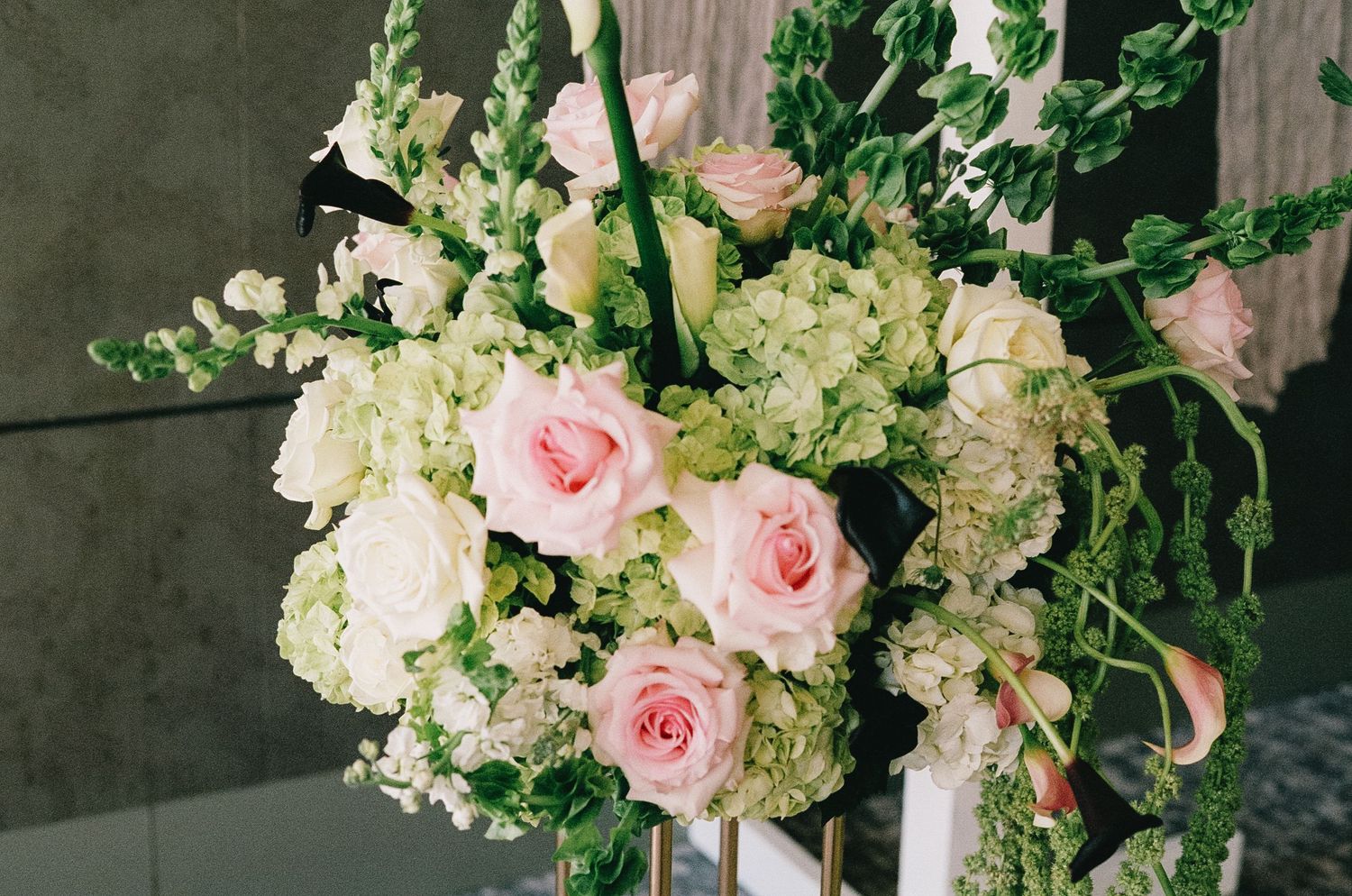 Elegant floral arrangement with pink roses and white hydrangeas against dark background.
