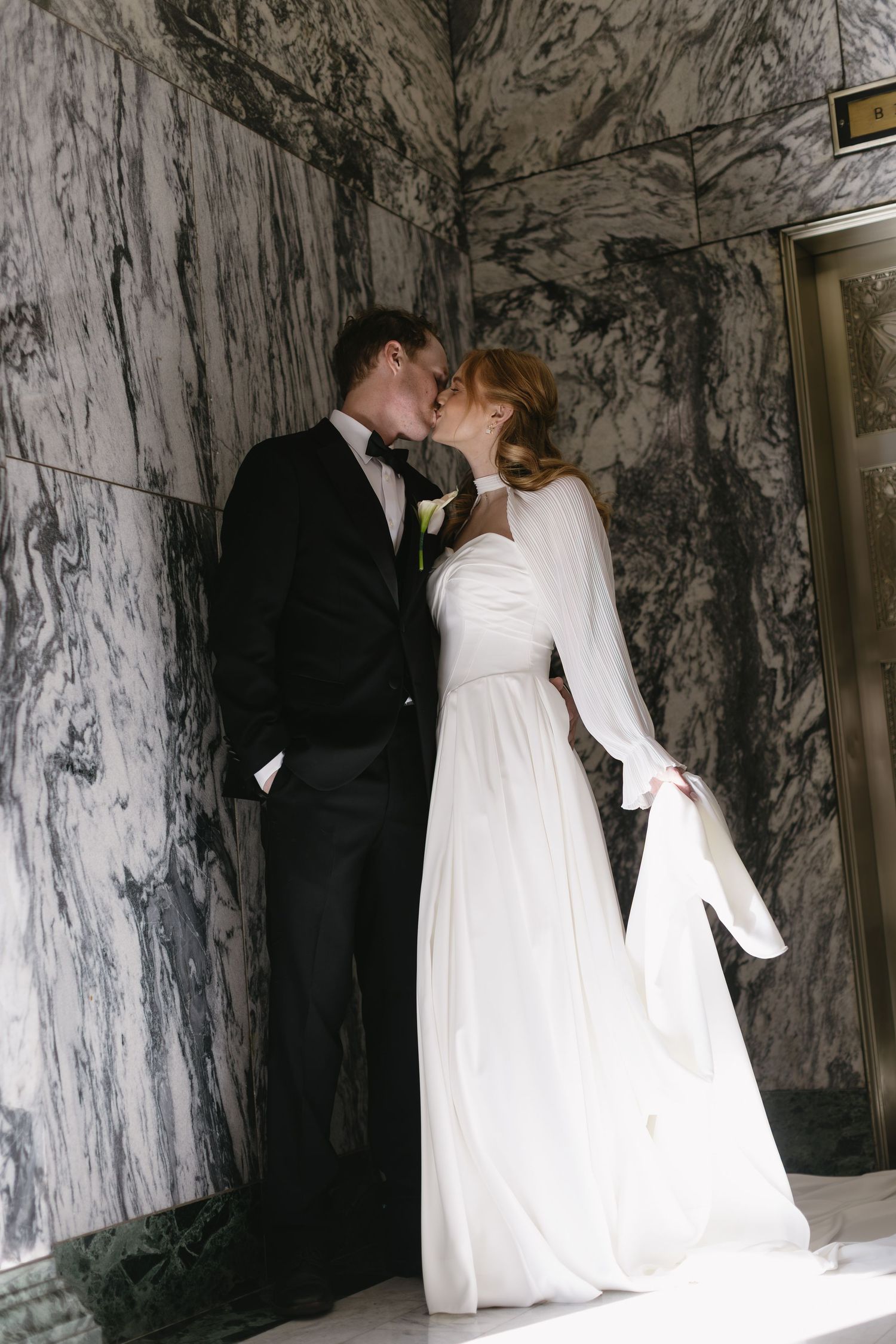 Romantic wedding moments captured against dramatic marble walls in an elegant indoor setting.