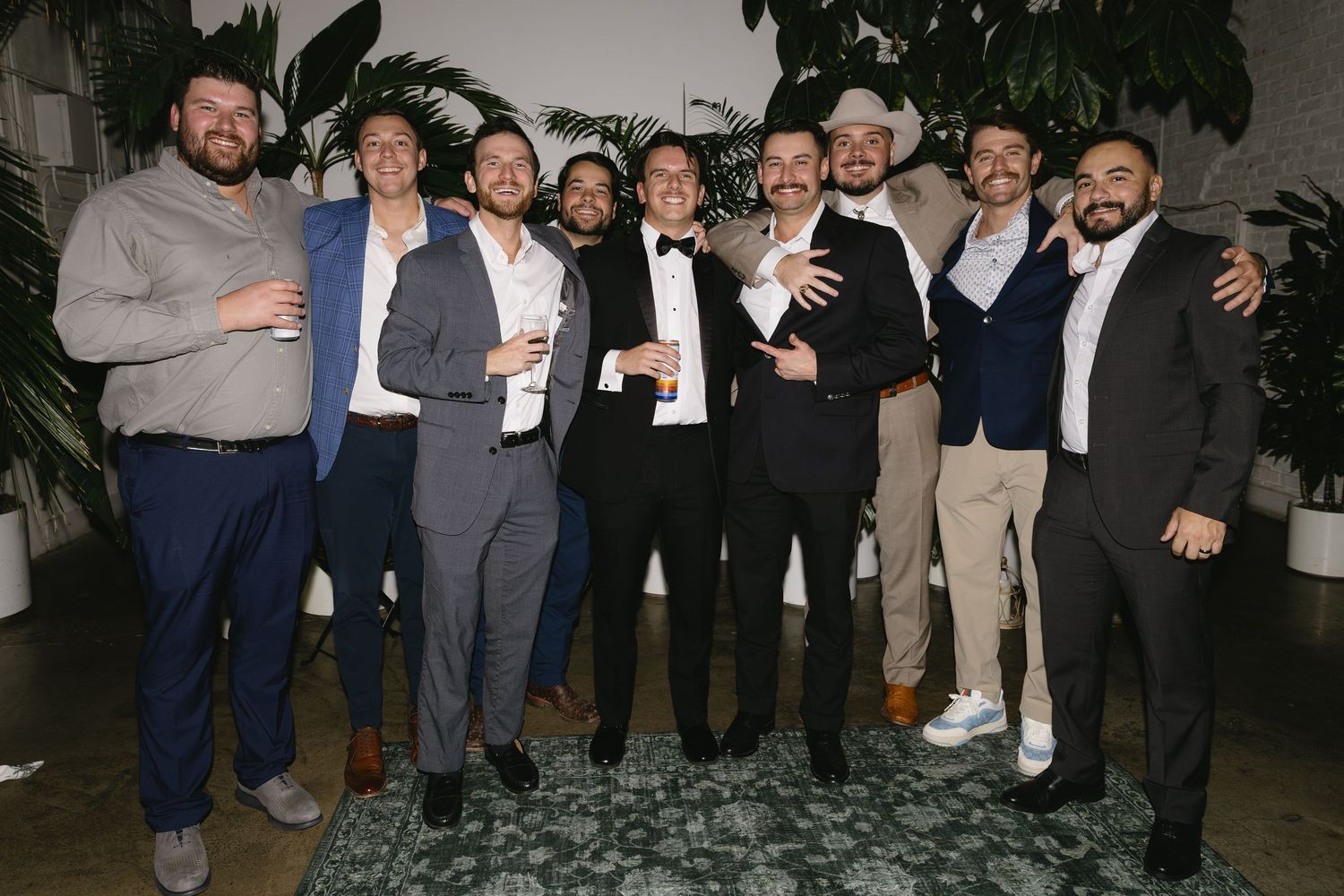 Group photo of wedding guests in formal attire at evening reception.