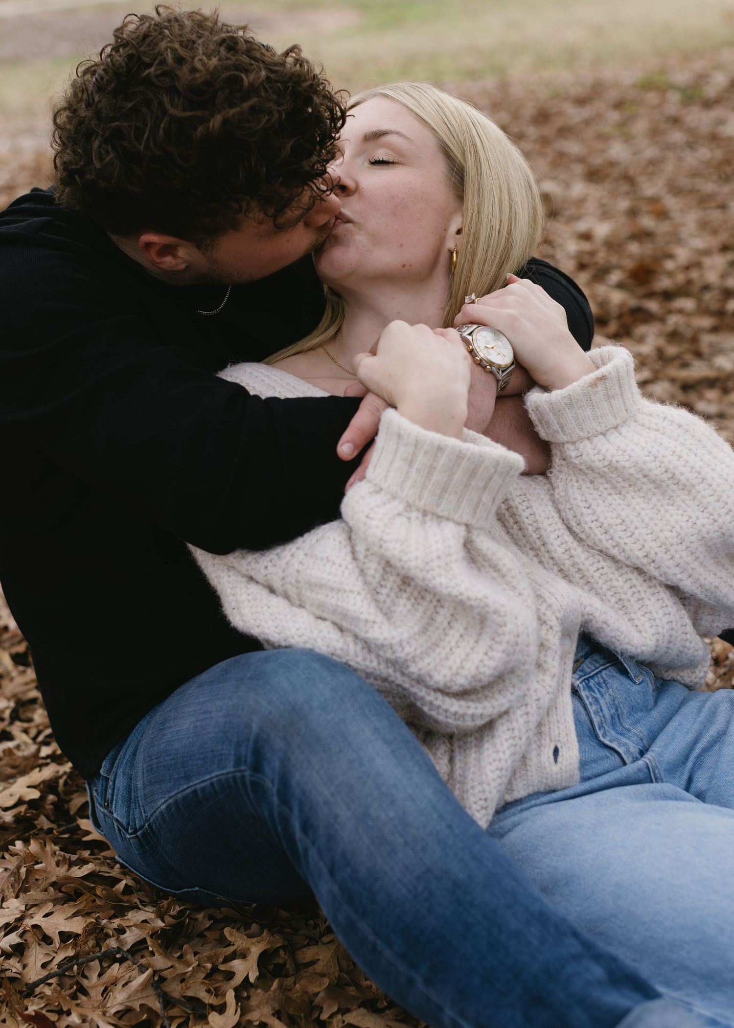 Romantic couple's photoshoot among fallen autumn leaves on the ground.