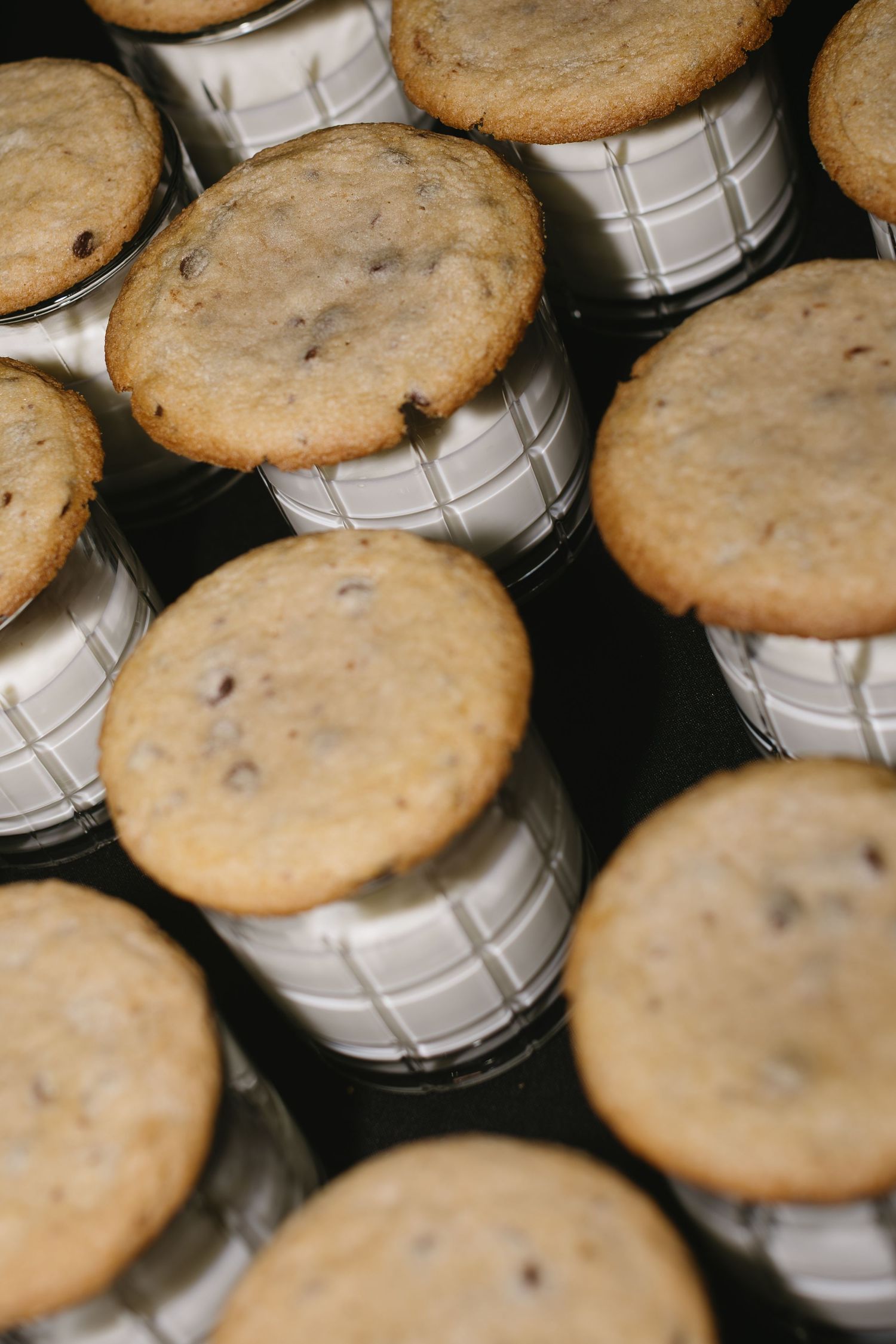 Homemade chocolate chip cookies arranged in rows on a white and gray checkered surface.