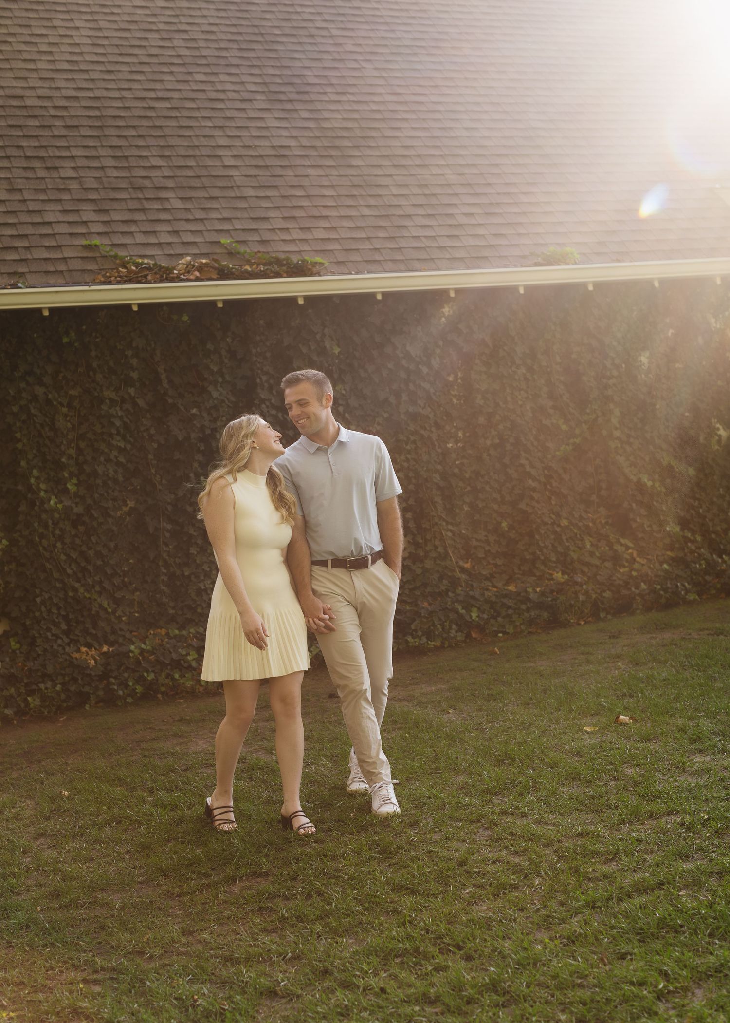 A couple shares a romantic moment together on a grassy lawn at sunset.