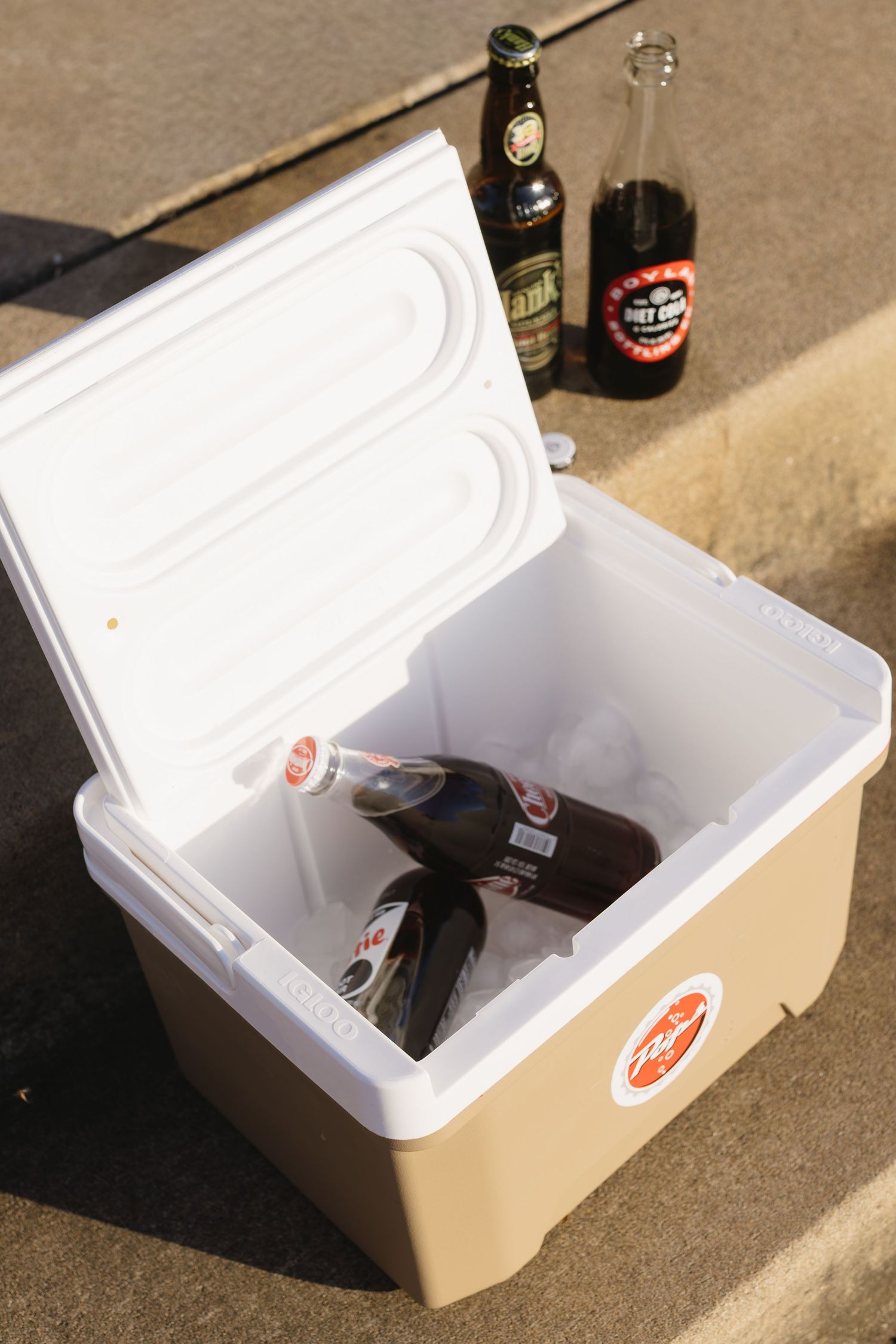 Step by step sequence showing bottles of beer being placed into a white styrofoam cooler.