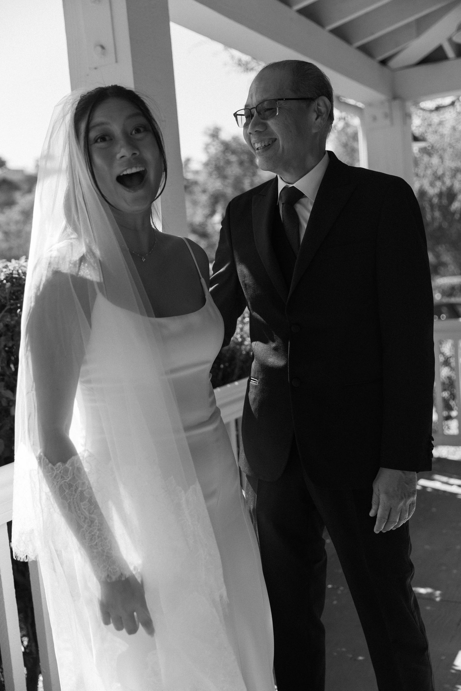Candid black and white wedding portraits showing laughter and joy on a porch.