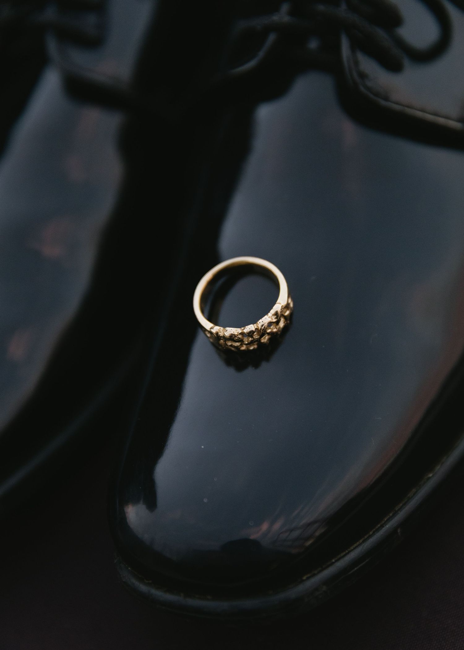 Diamond wedding ring artistically photographed on reflective black surface.