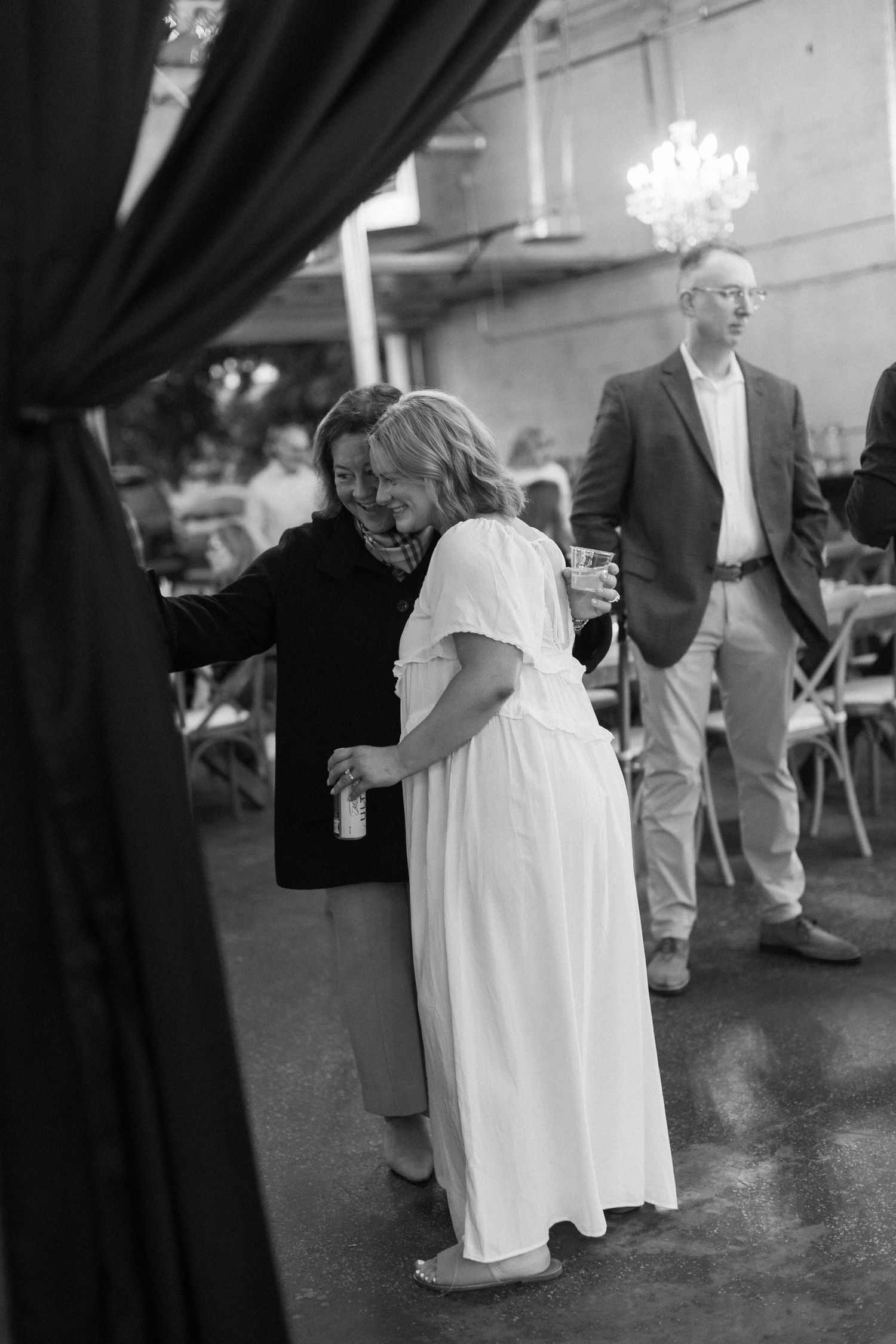 Black and white photo of guests mingling at an elegant indoor reception.