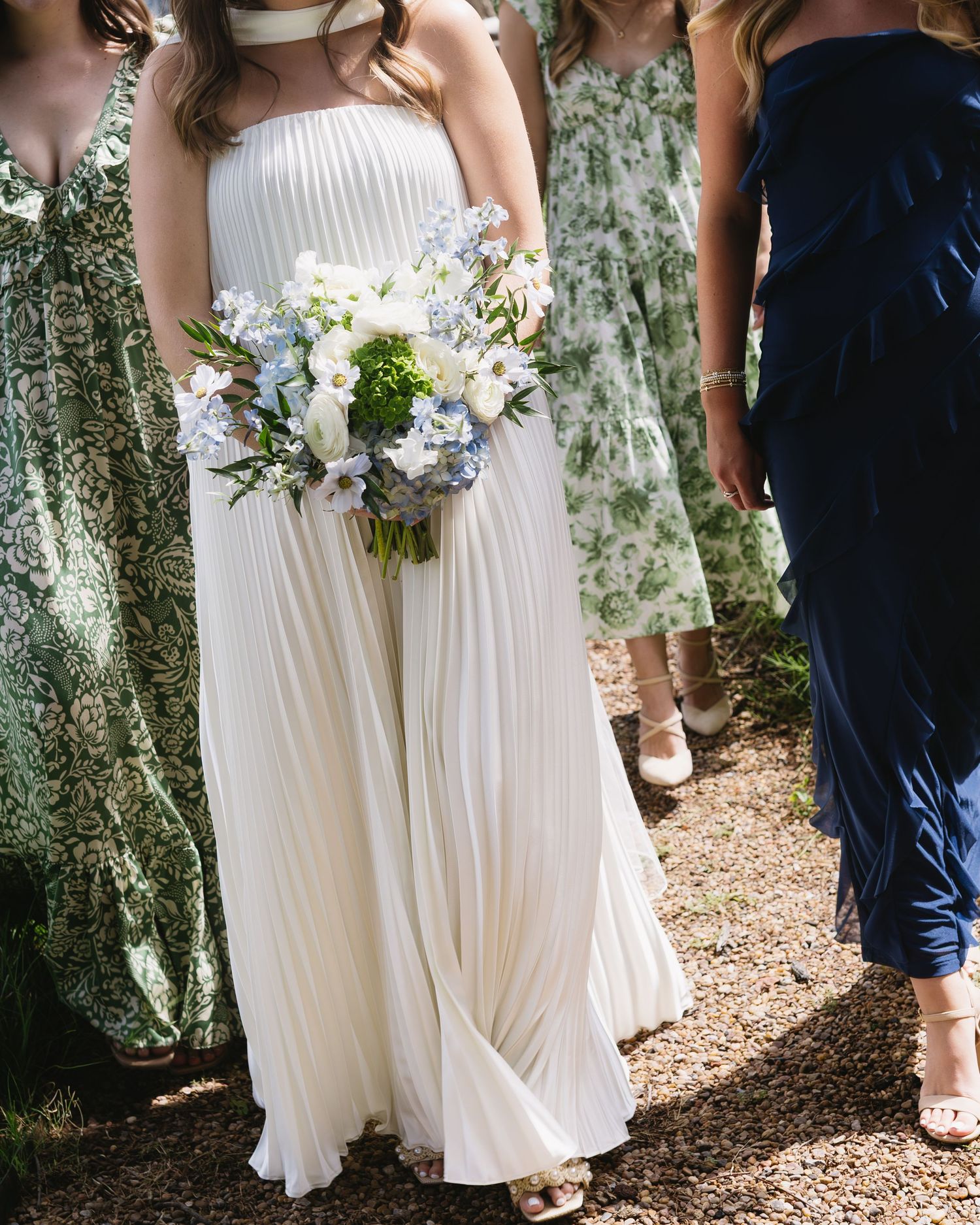 Wedding party wearing navy and white attire standing on woodland path.