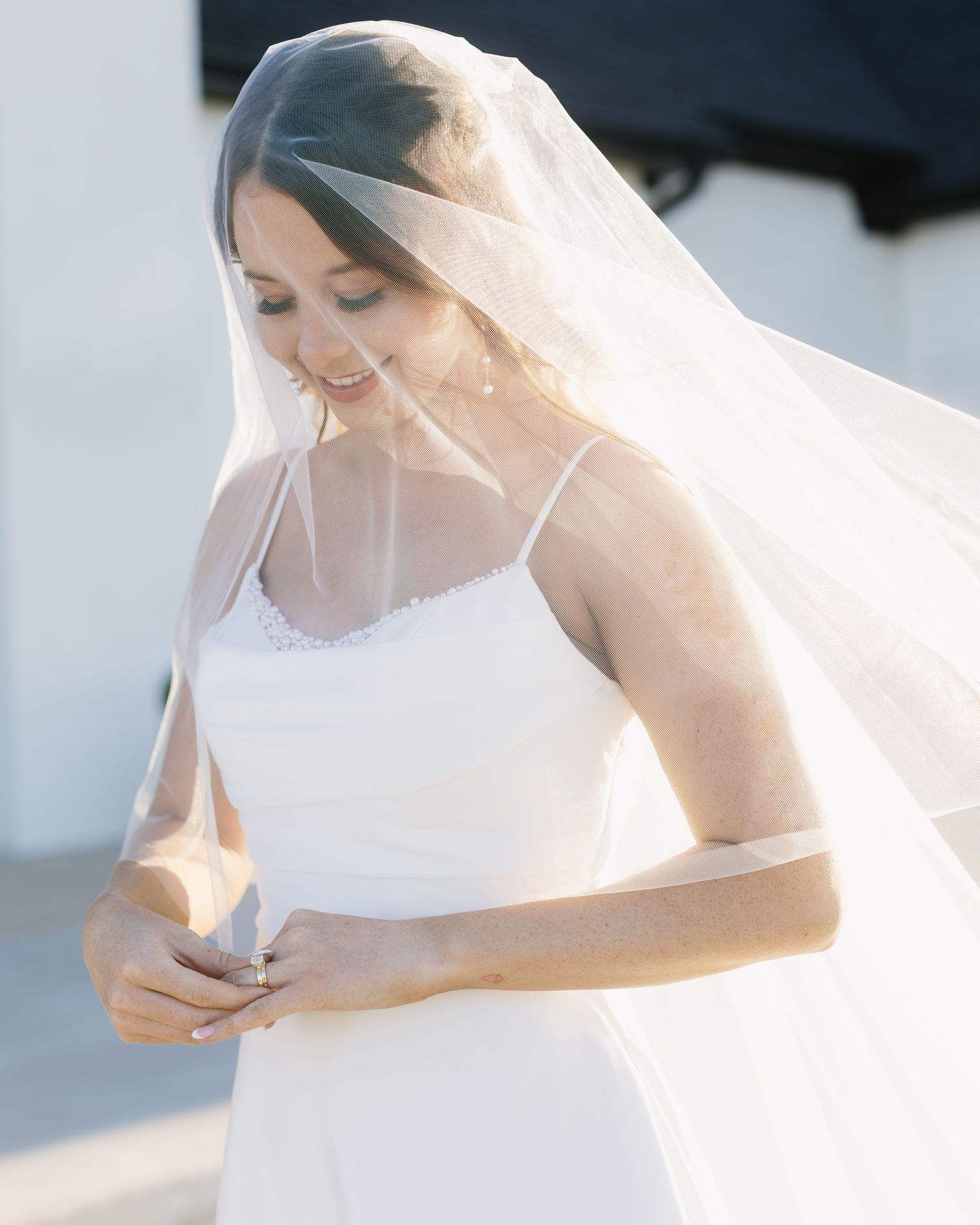 An elegant white bridal gown is showcased with delicate lace details and flowing veil.