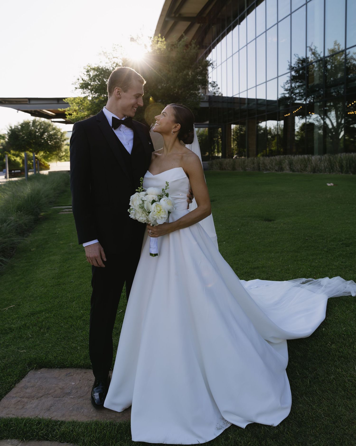 Wedding couple sharing a romantic moment outside a modern glass building.