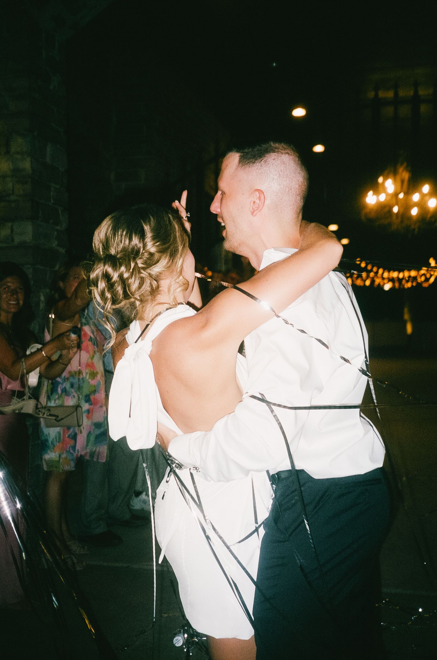 Couples dance together at a dimly lit nighttime party or celebration venue.