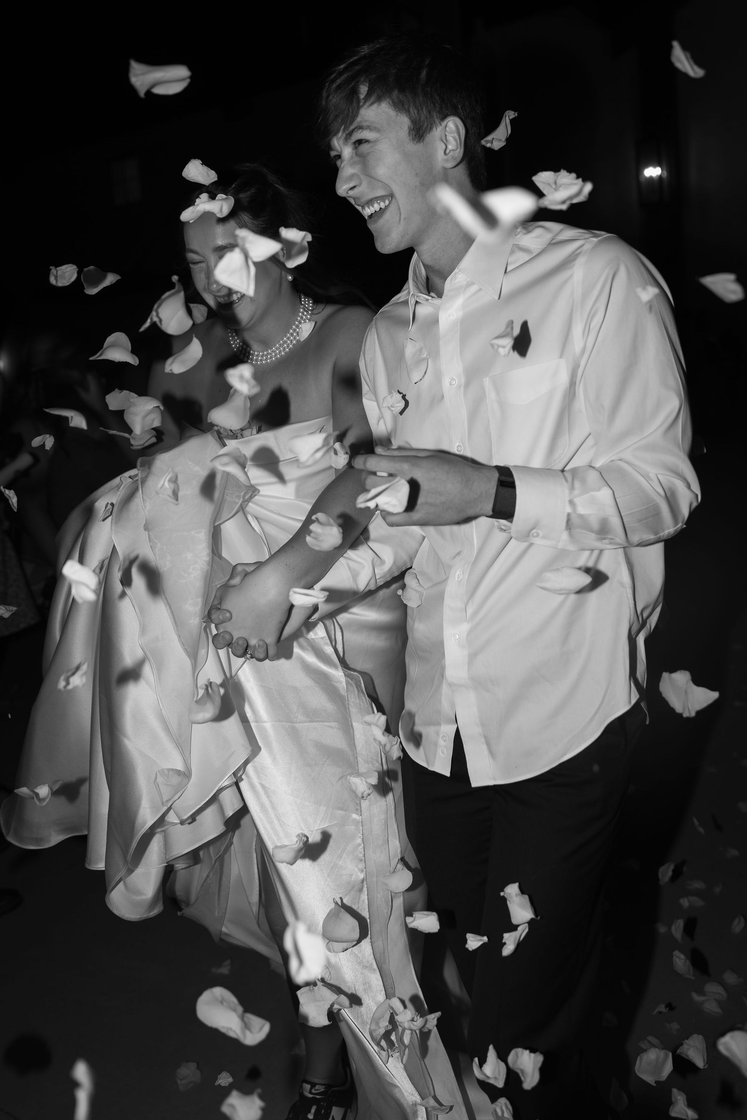 Black and white photo of joyful celebration with confetti falling around celebrating couple.