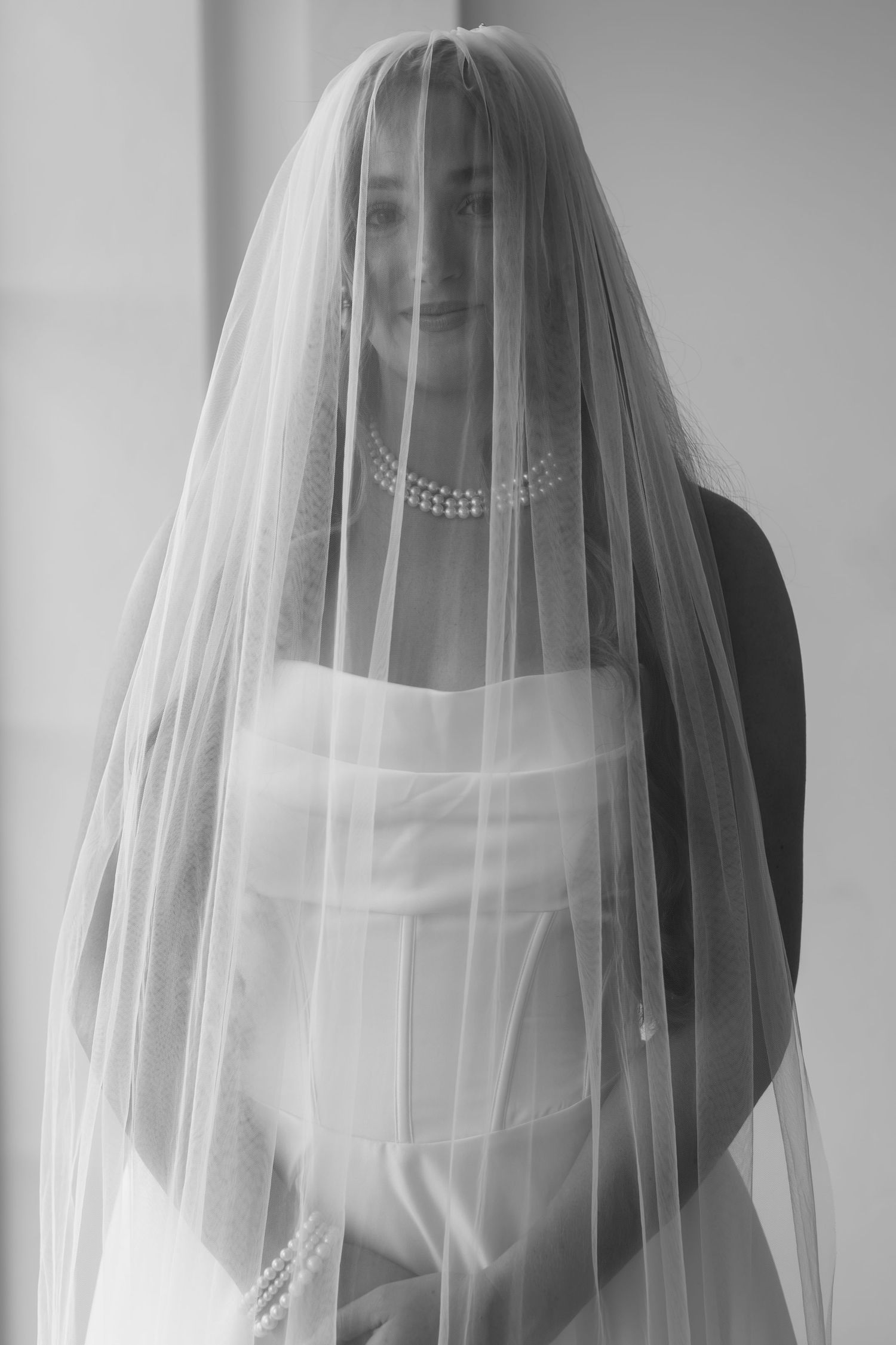 Delicate bridal portraits through sheer white veil in black and white photography.