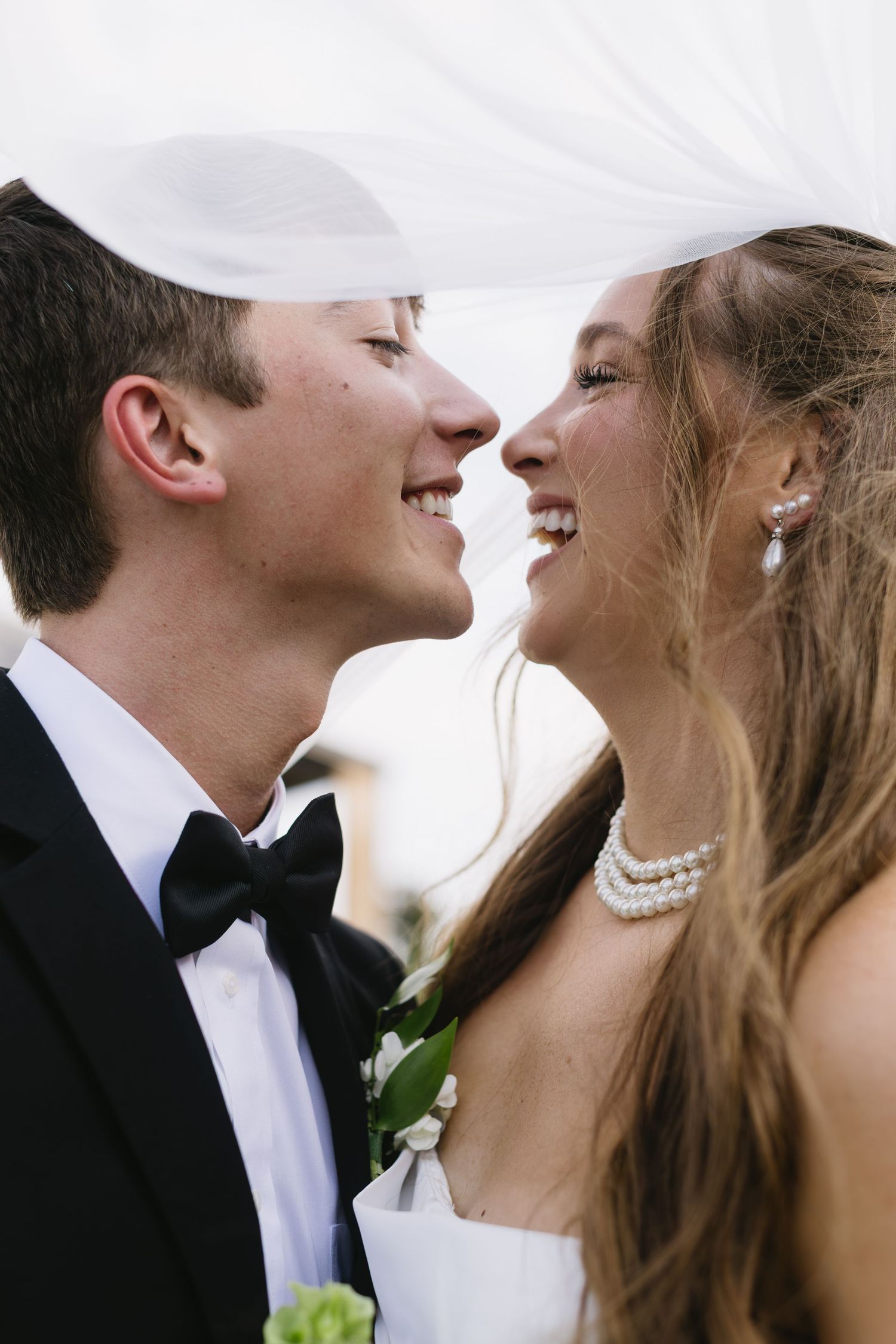 A romantic wedding couple sharing an intimate moment in black and white with matching formal attire.