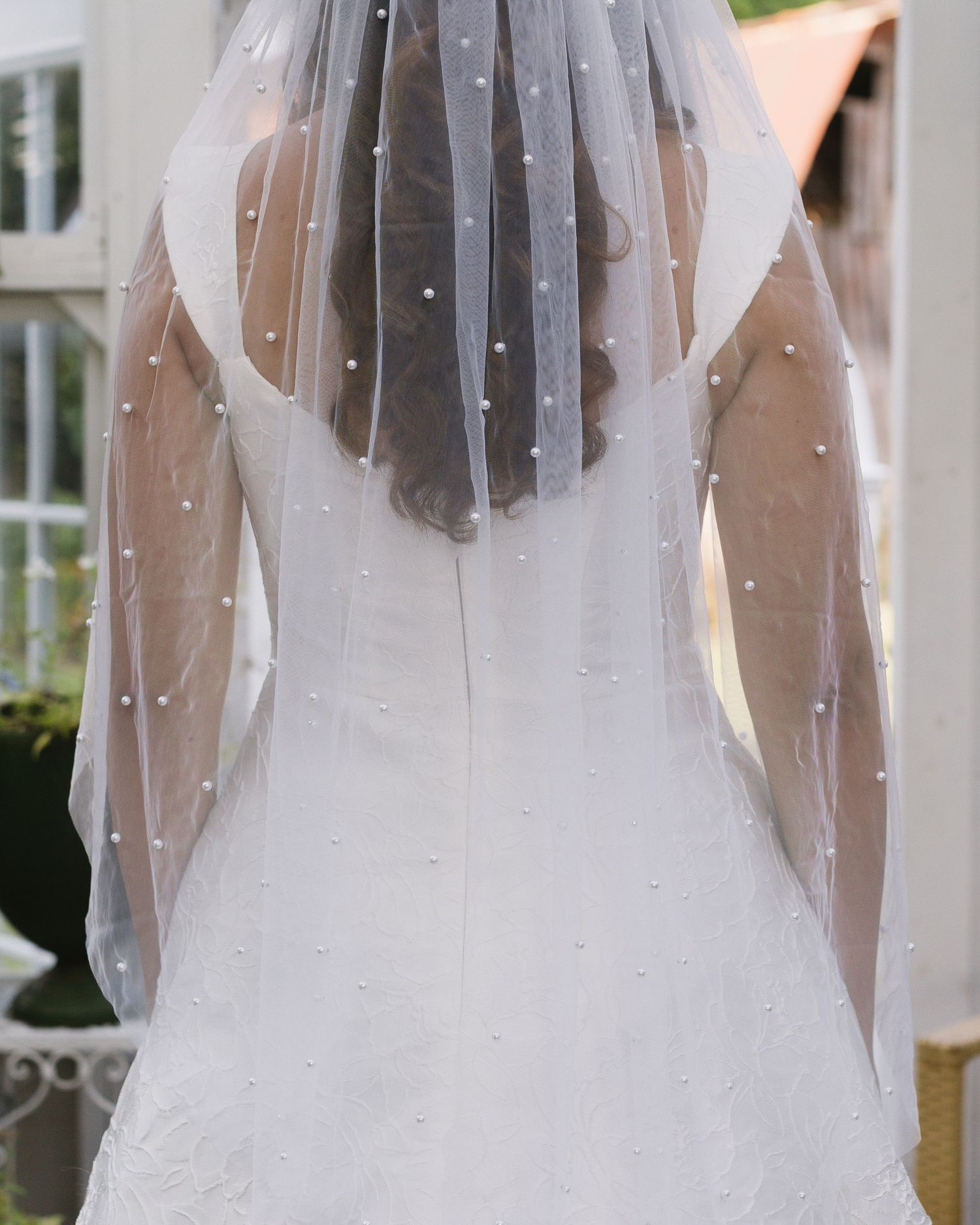 Delicate polka dot wedding veil detail photographed against white dress in natural light.