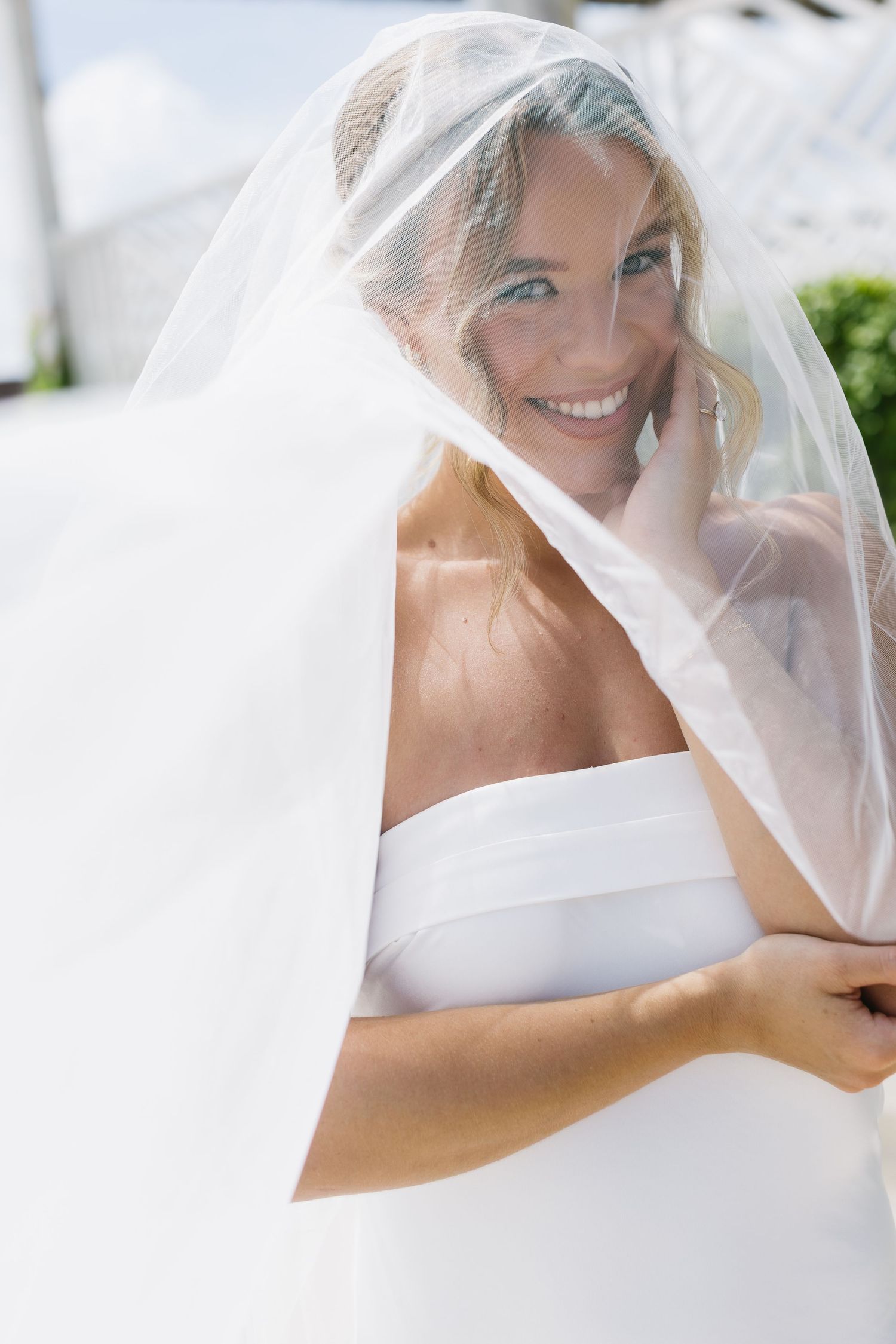 Close-up of bride with veil showing natural joy during wedding day preparations.