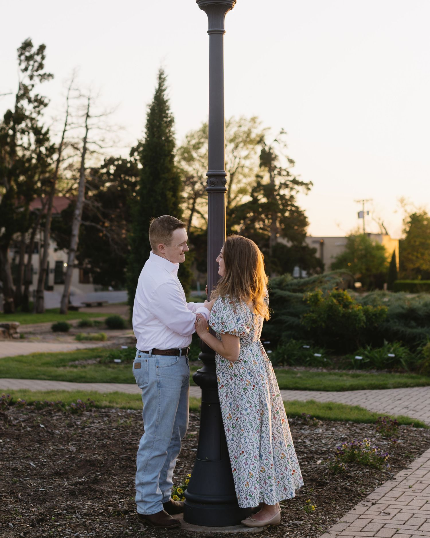 A couple poses together near a vintage lamp post during a sunset photo session.