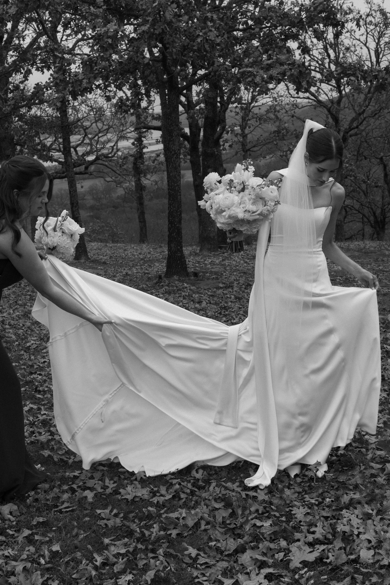White wedding dress flowing dramatically in the wind against a backdrop of autumn trees.