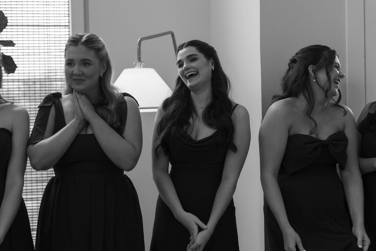 A group in black dresses react emotionally during a wedding preparation moment.
