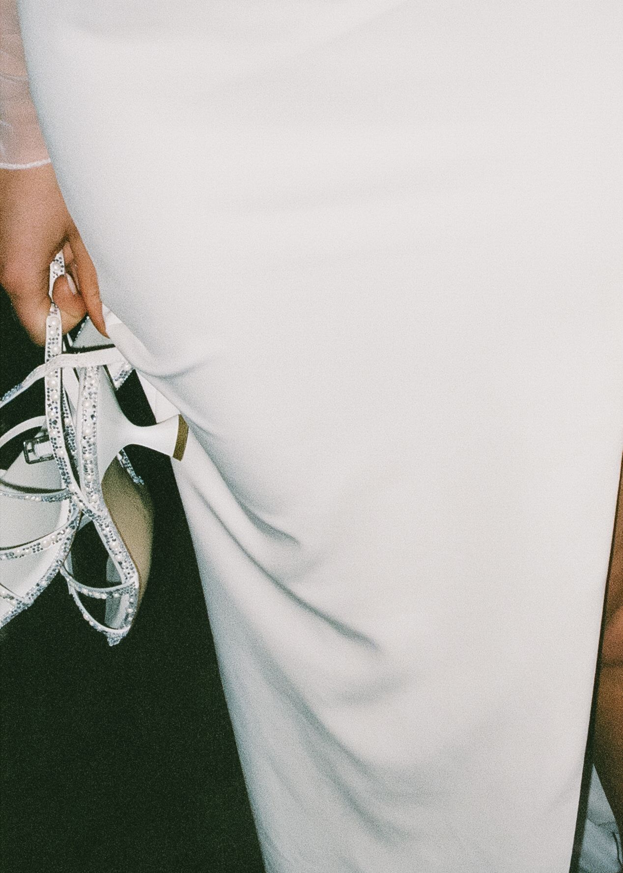 Close-up view of white shoelaces being tied on black sneakers against a white background.