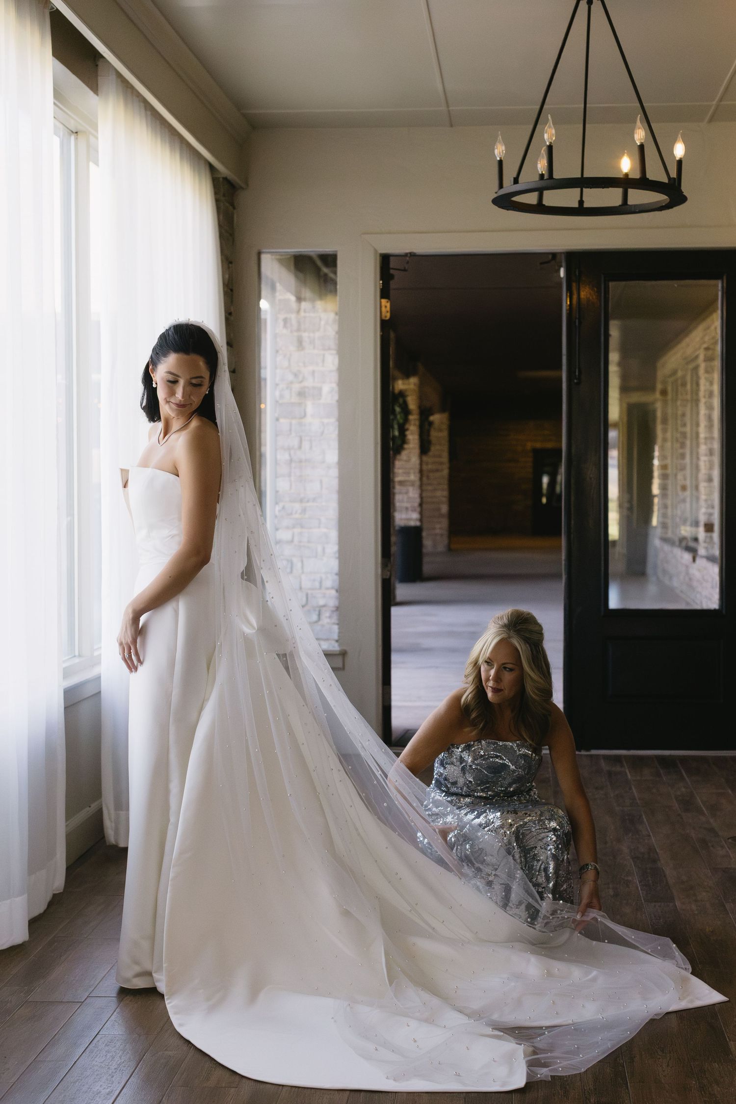 Elegant white wedding dress with long train in a sunlit hallway.