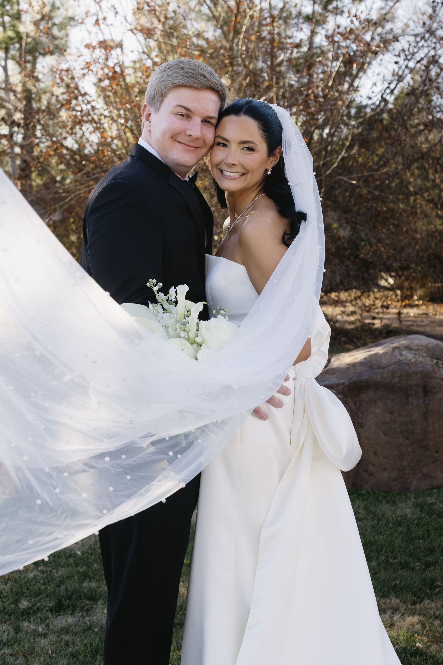 Wedding couple poses for romantic portraits in a natural outdoor setting with autumn foliage.