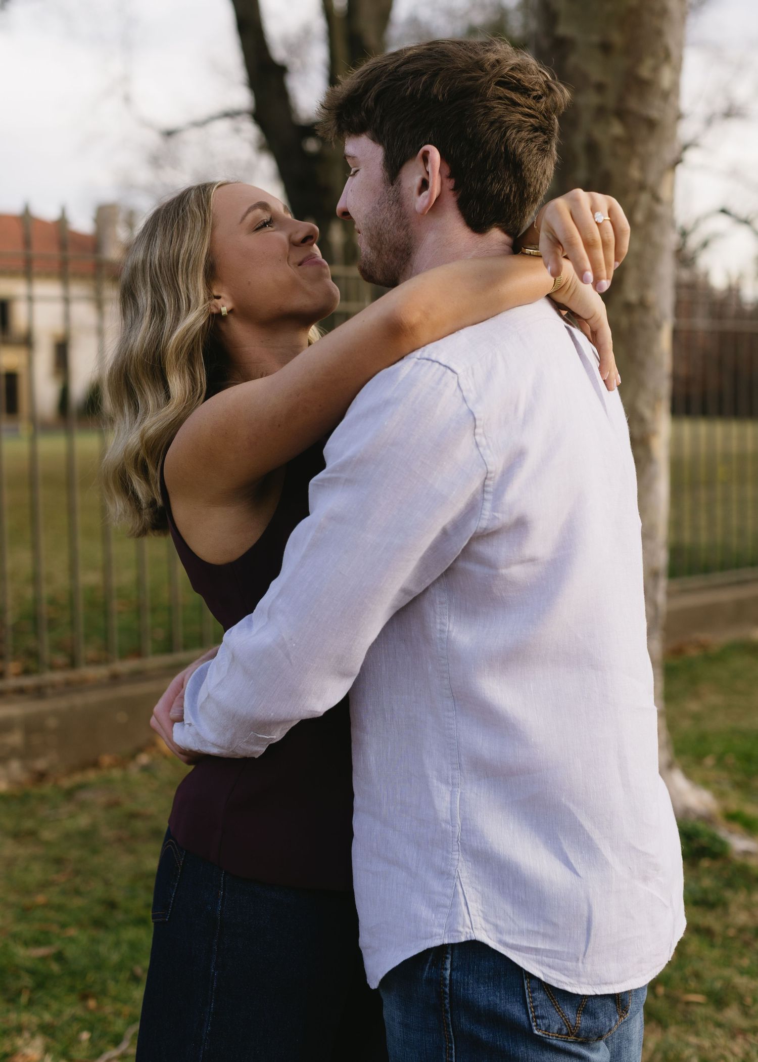 A couple shares a tender embrace outdoors during a casual photo session.