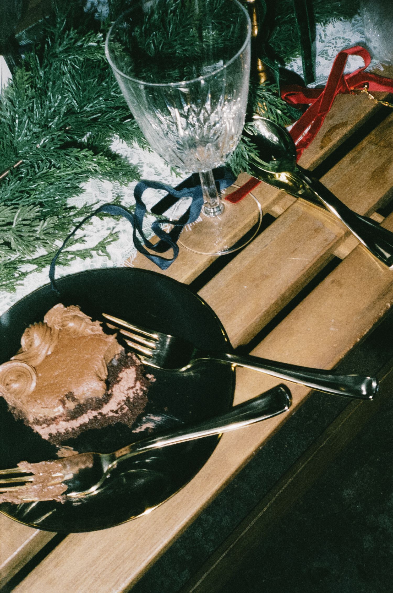 Wedding reception dessert plates with chocolate cake and evergreen decor.