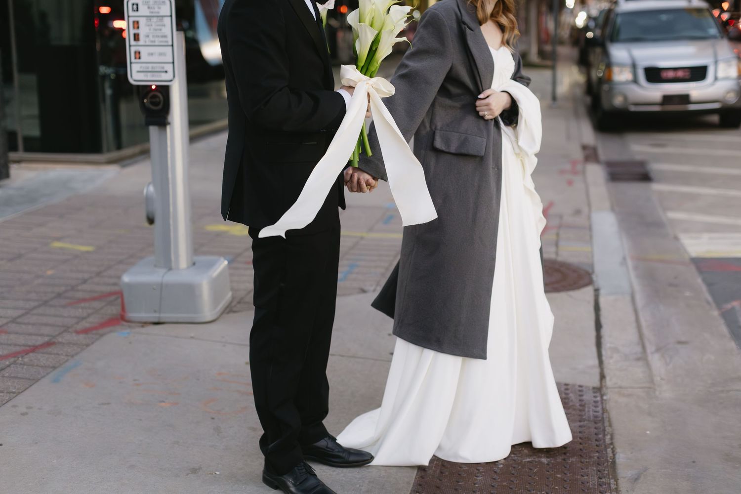 Newlyweds walk together on an urban street after their wedding ceremony.