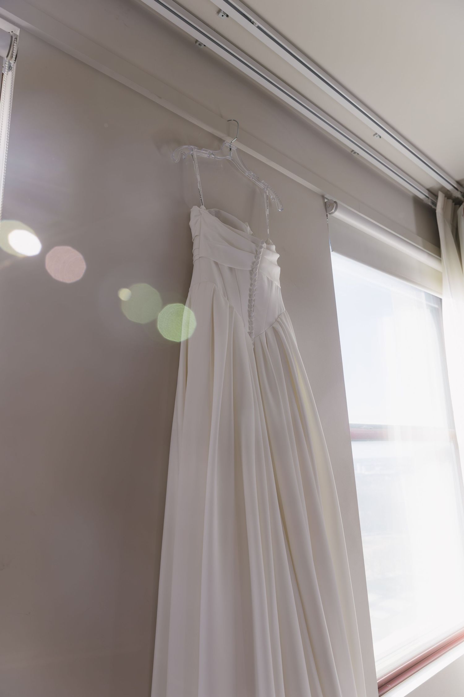 White curtains hanging from ceiling mounted tracks in a bright room with natural lighting.