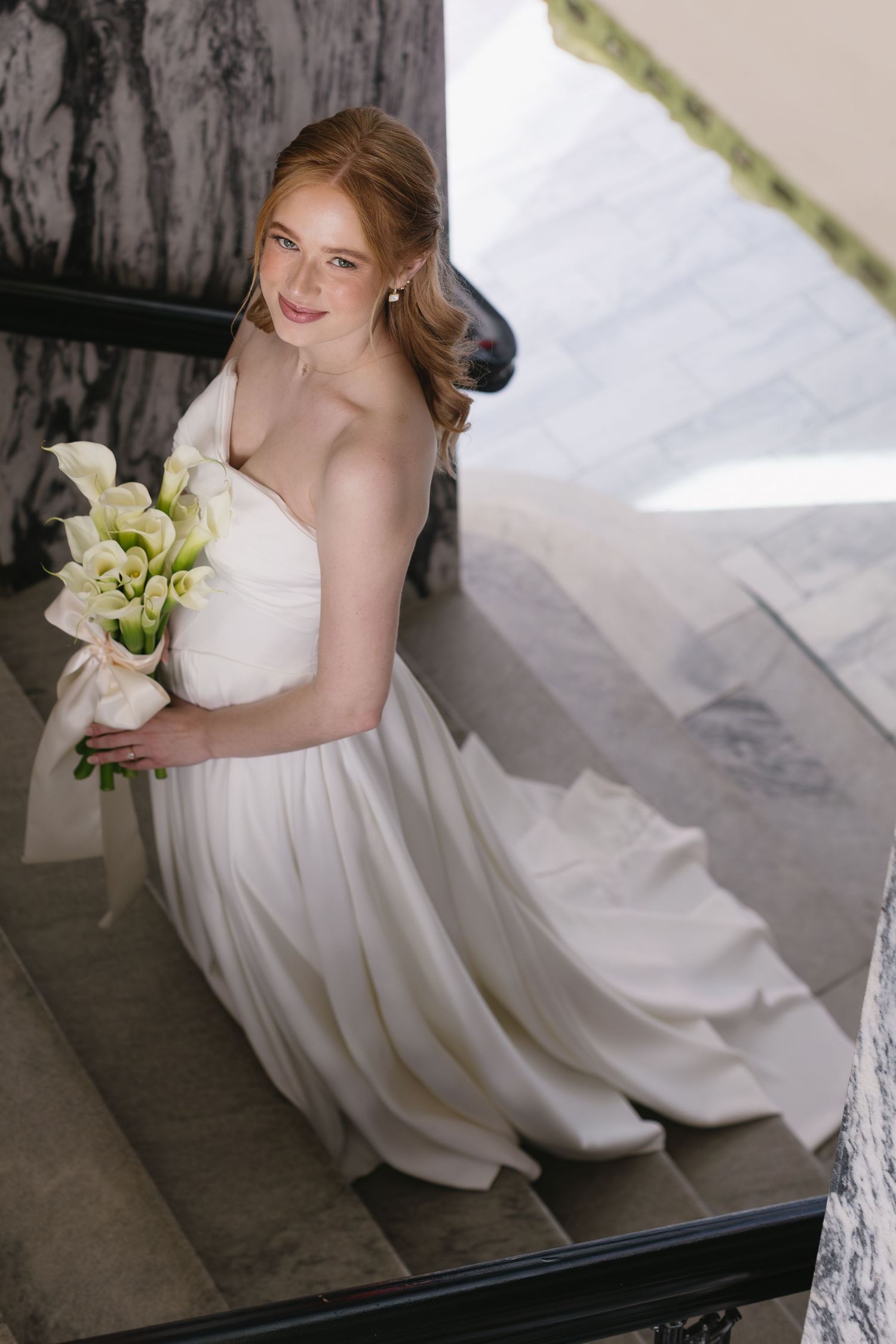 Elegant bridal portrait with white calla lily bouquet and flowing dress.