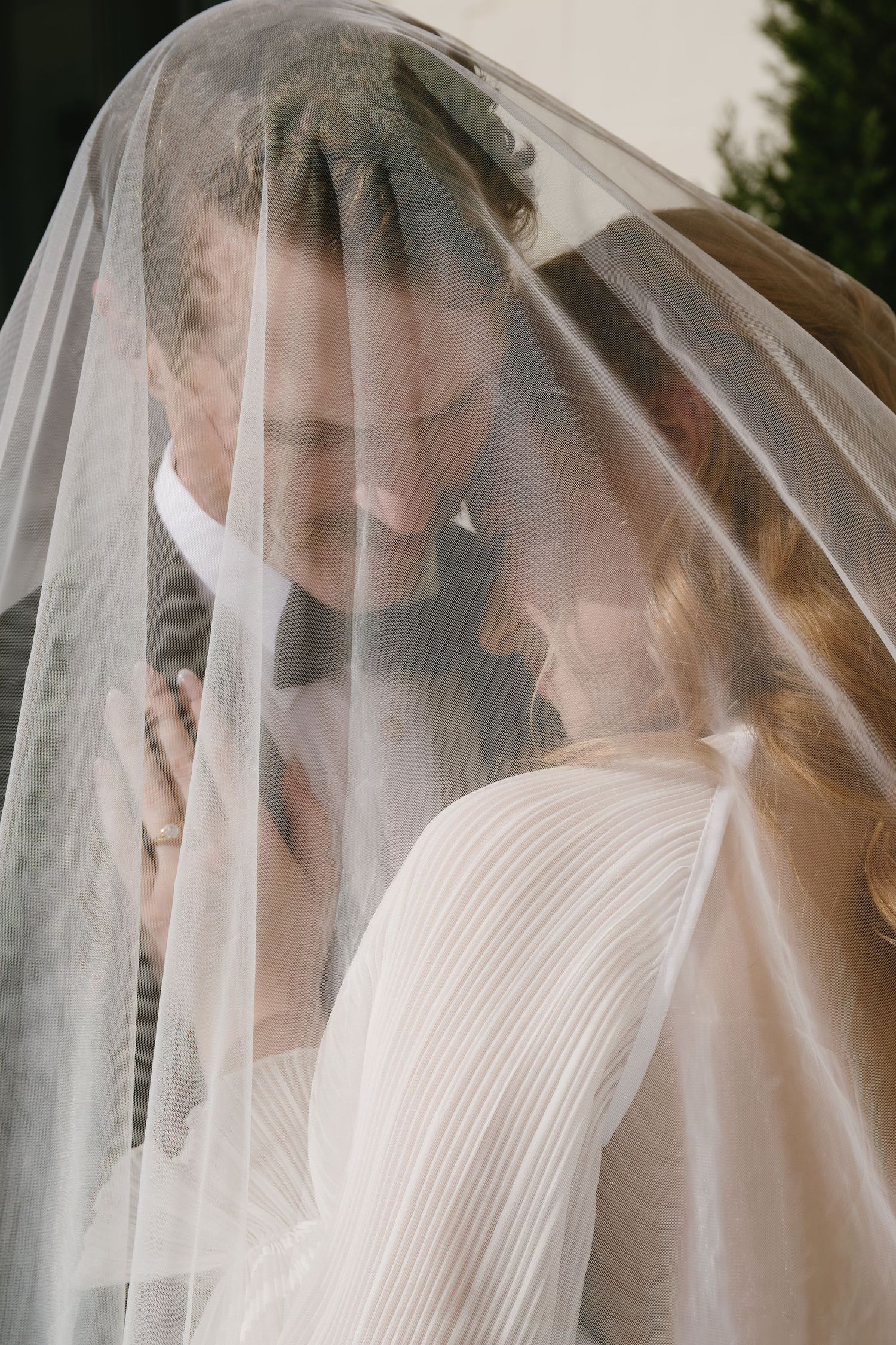 A delicate bridal veil creates a soft, romantic effect in close-up wedding photography.