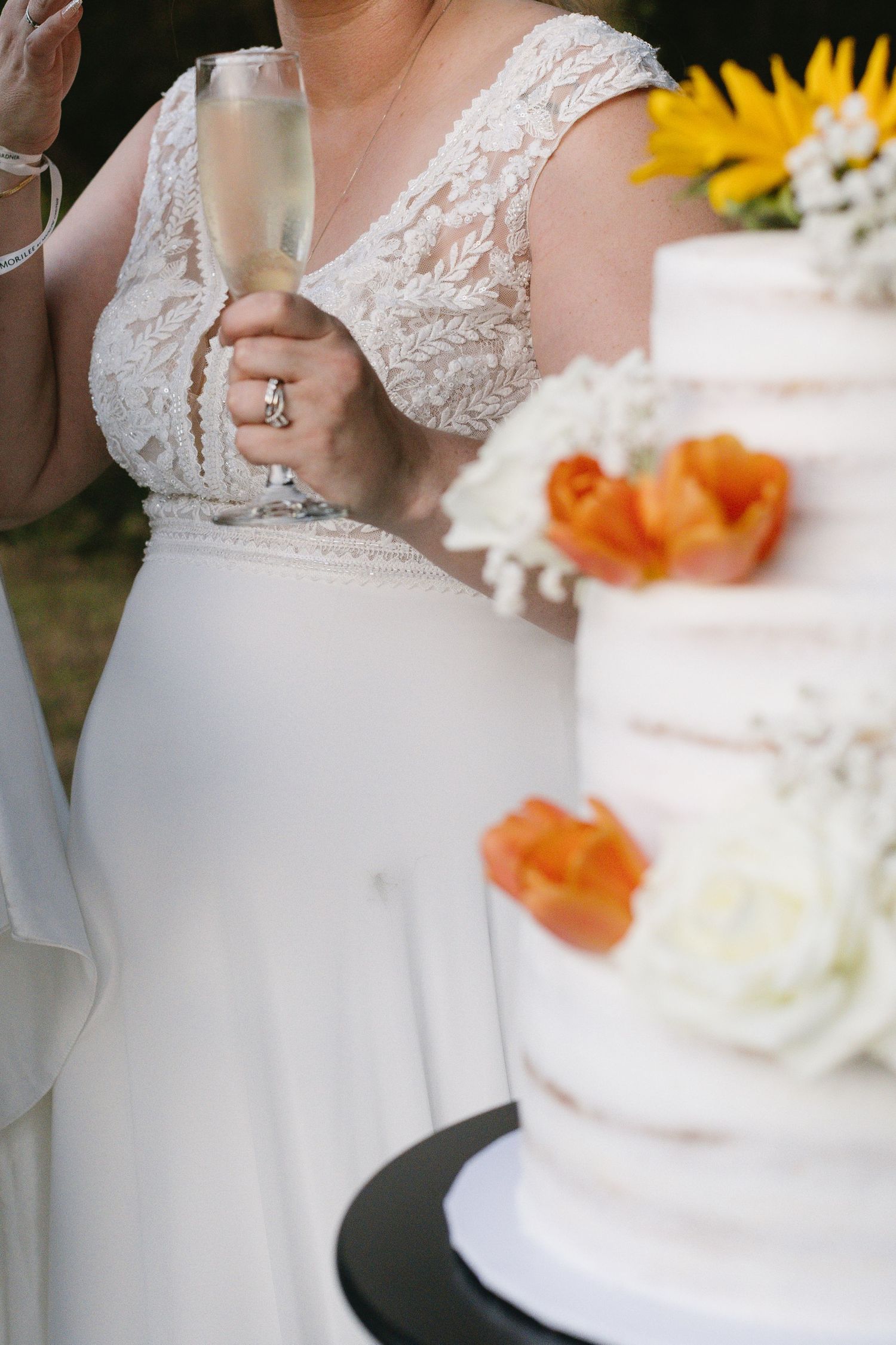 Close-up of a white wedding dress and cake decorated with orange and white flowers.