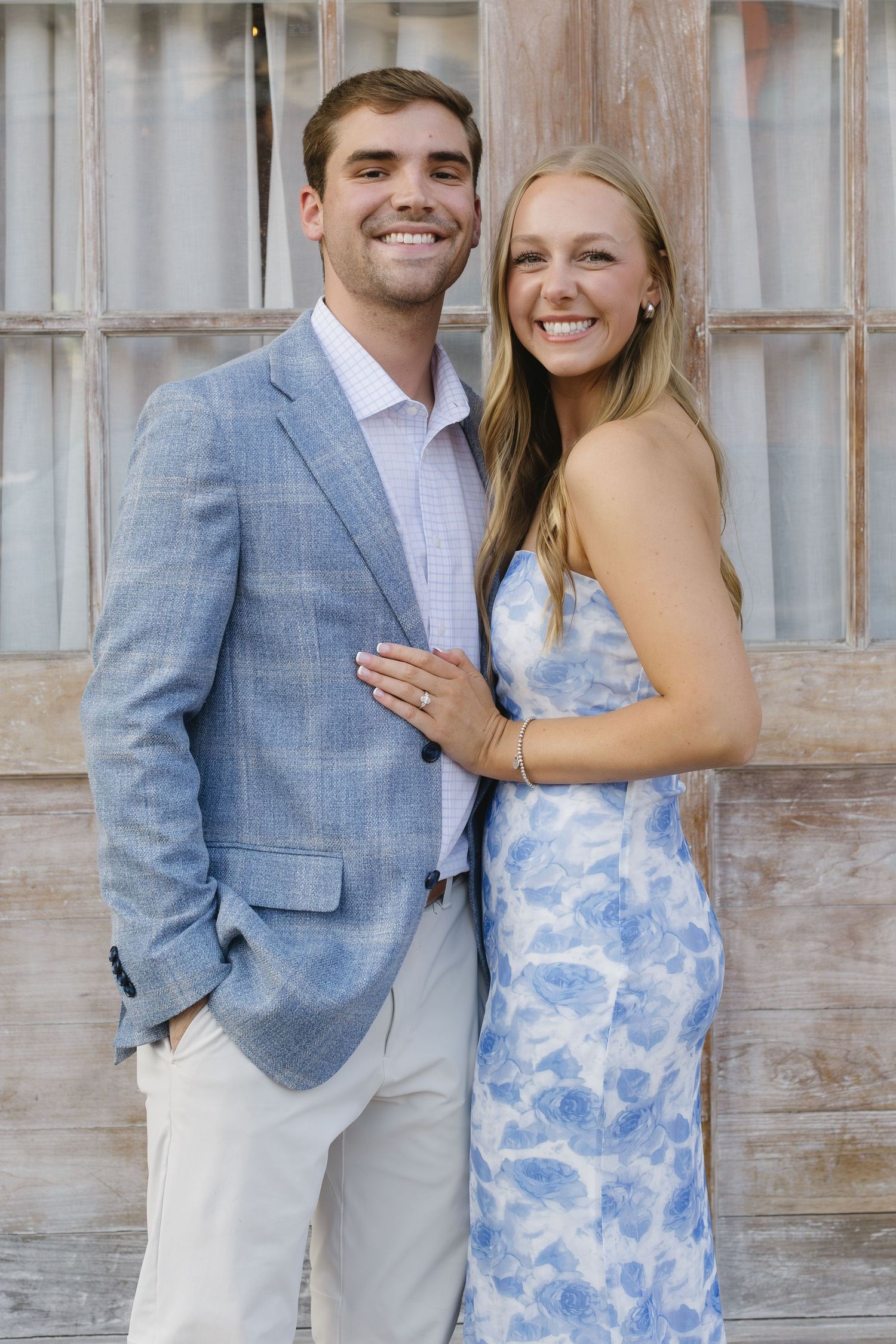 A couple poses outdoors wearing coordinated blue and white outfits.