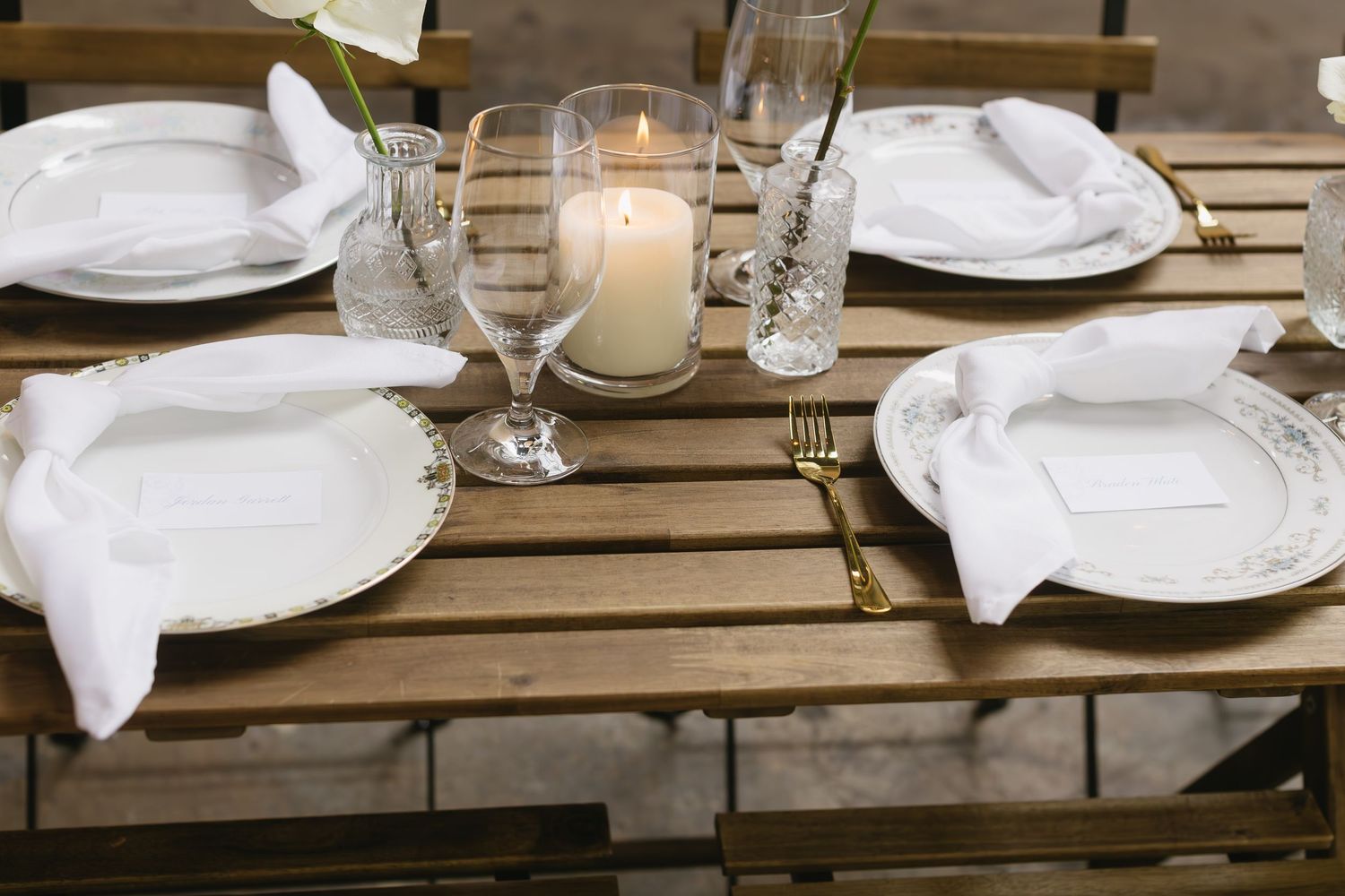 Close-up of minimalist place settings with white linens on wooden tables.