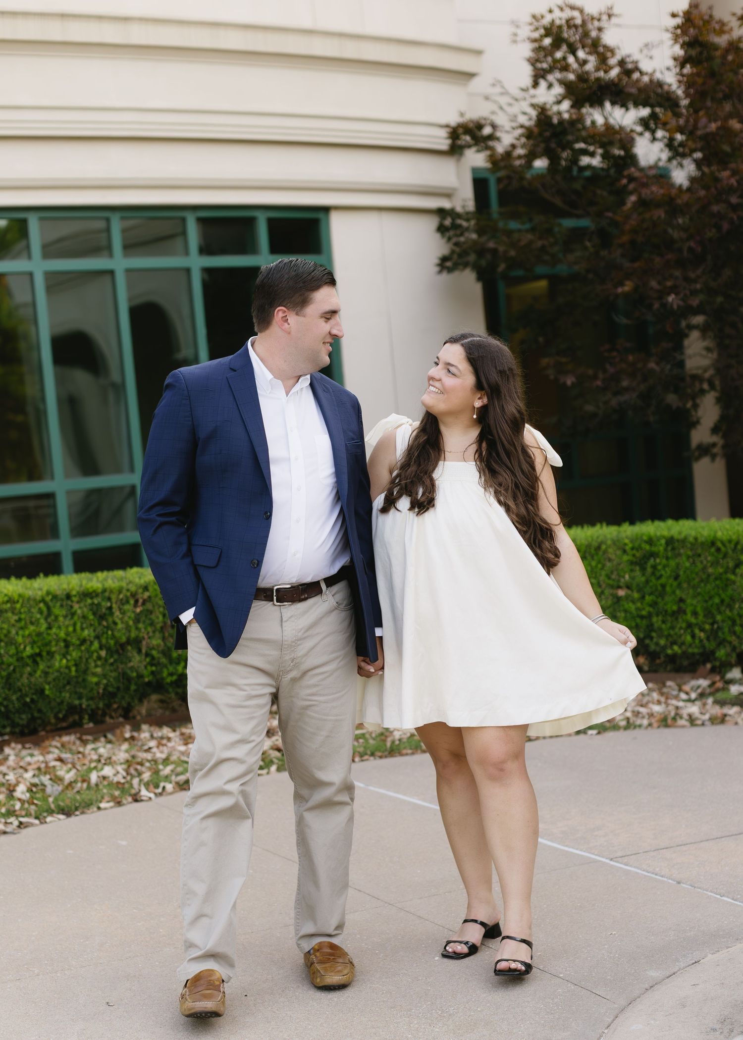 A couple walking together outside a modern building with curved architecture.