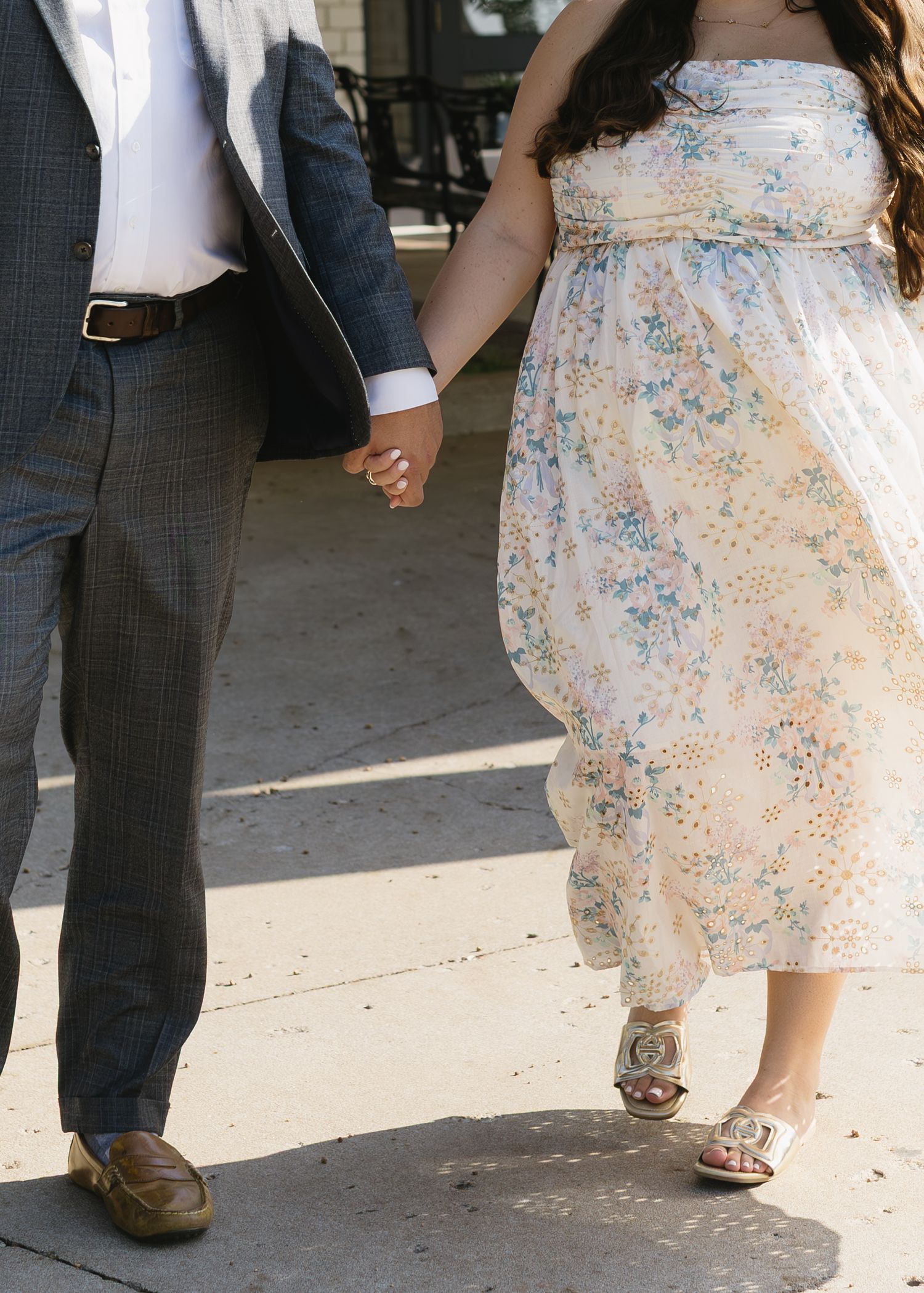 Close-up view of a couple's feet during their wedding dance, with the bride wearing a floral dress and sandals.