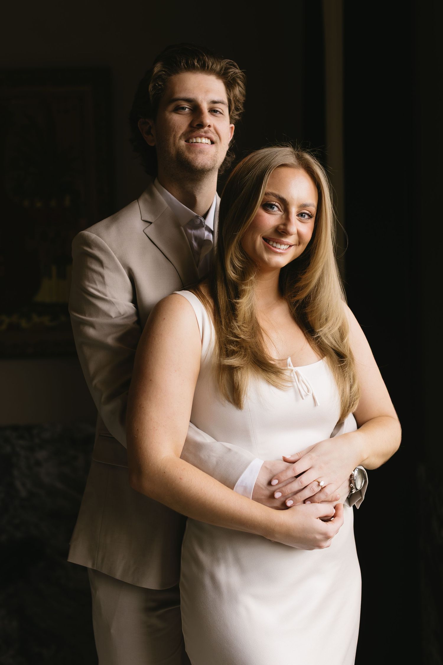 A couple in white embraces in an intimate indoor portrait session.