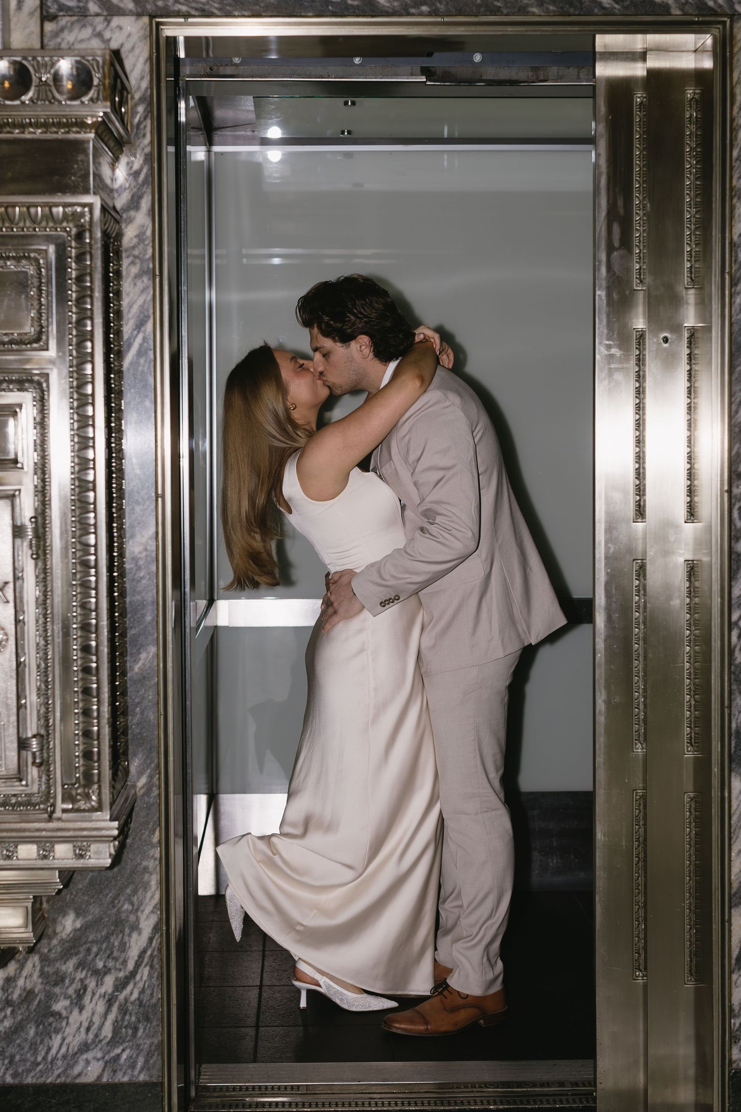 Romantic couple shares intimate moments in an ornate vintage elevator.
