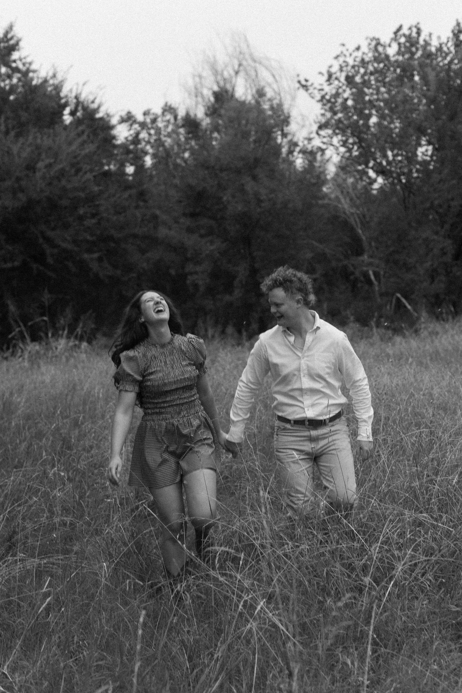 Black and white photo series of couple running and laughing through tall grass.