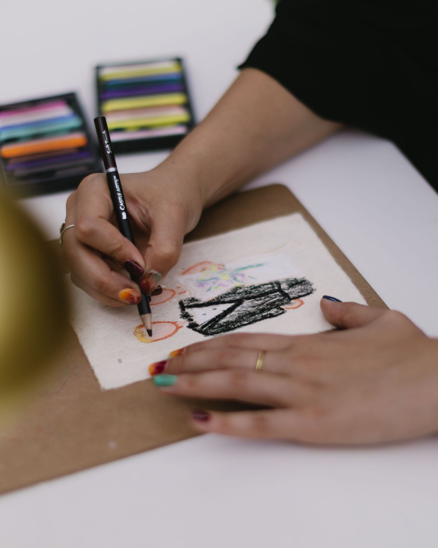 Artist's hands with colorful nail polish drawing a fashion sketch with watercolor paints.