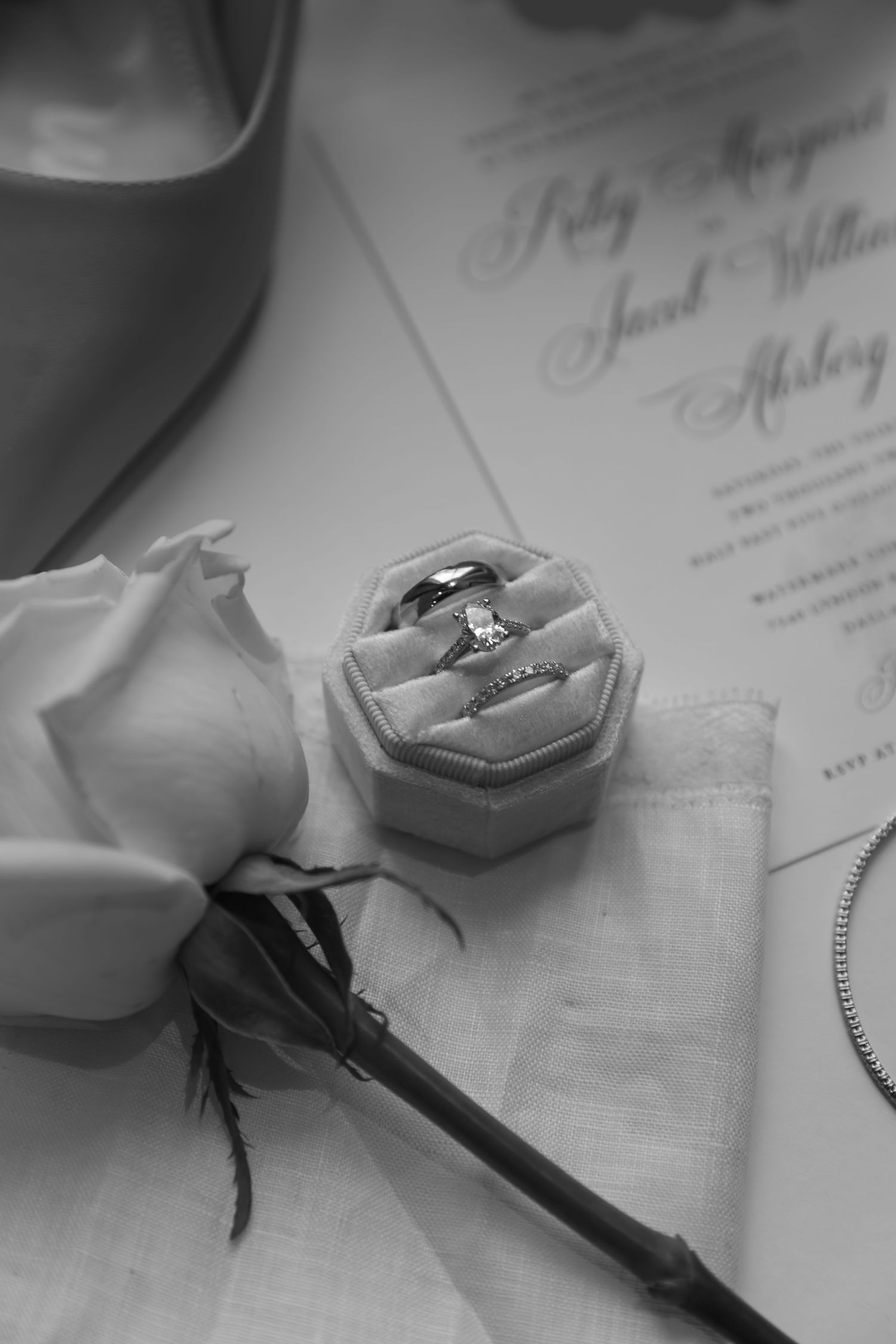 Close-up sequence of signing a document with a wedding ring displayed in foreground on a textured white surface.