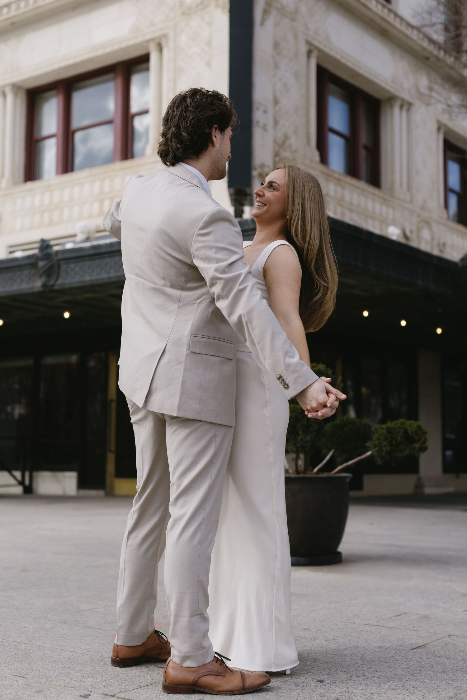 A couple dances together in formal wear on an outdoor plaza.