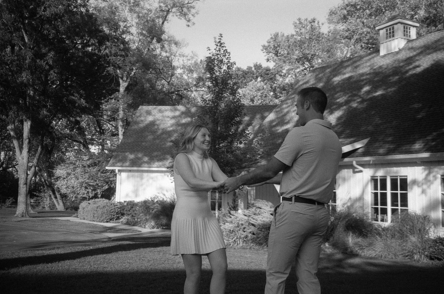 Black and white film strip showing a couple walking together on a residential street in vintage clothing.