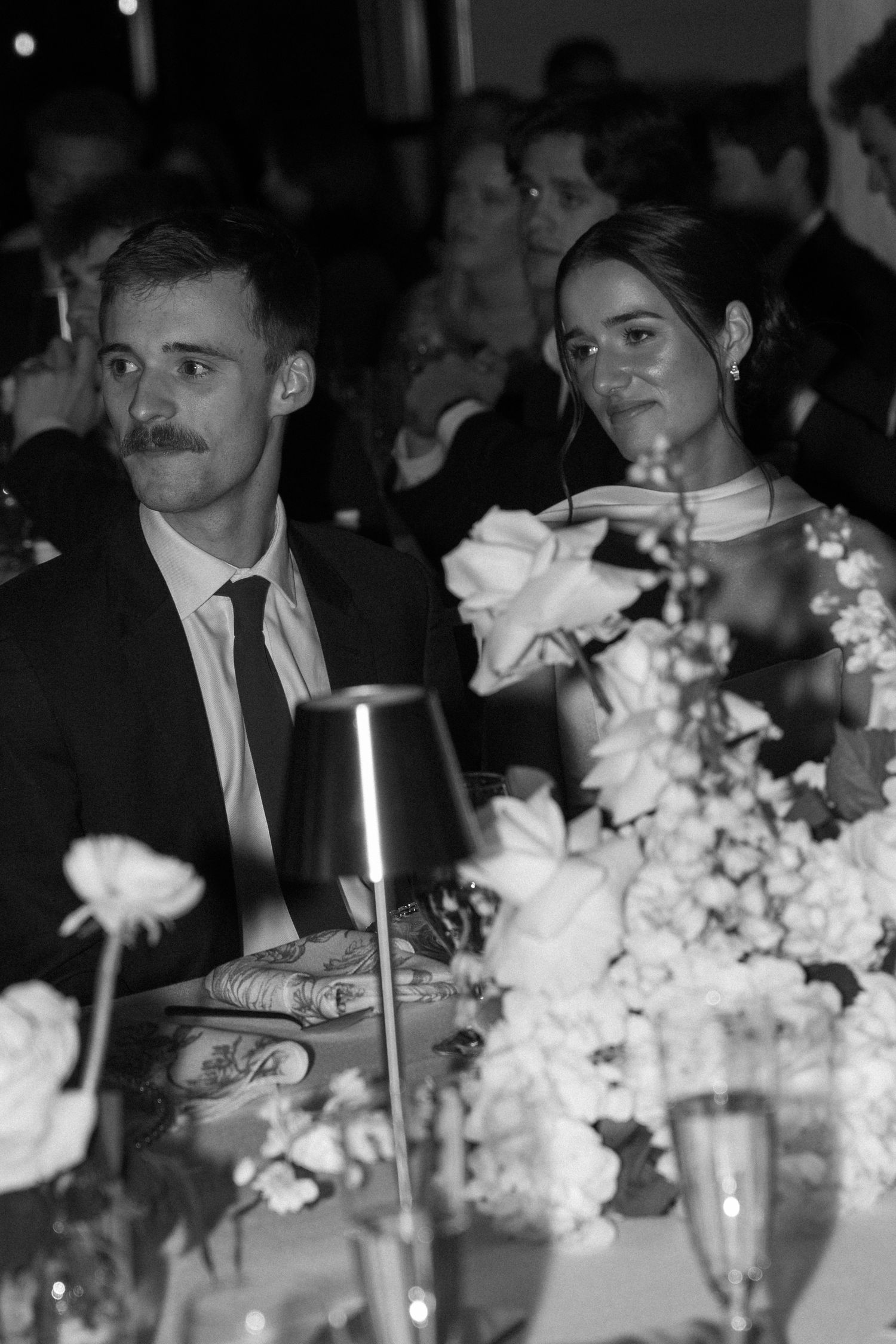 Black and white reception photo with candlelit tables decorated with white floral centerpieces.